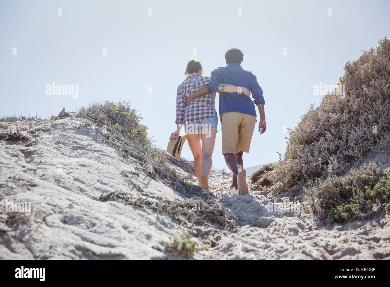Coppia affettuosa che cammina lungo il soleggiato sentiero della spiaggia estiva Foto Stock