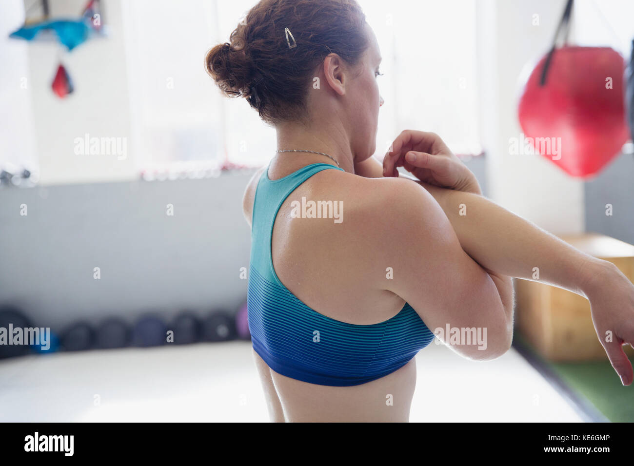 Donna che allunga il braccio e le spalle in palestra Foto Stock