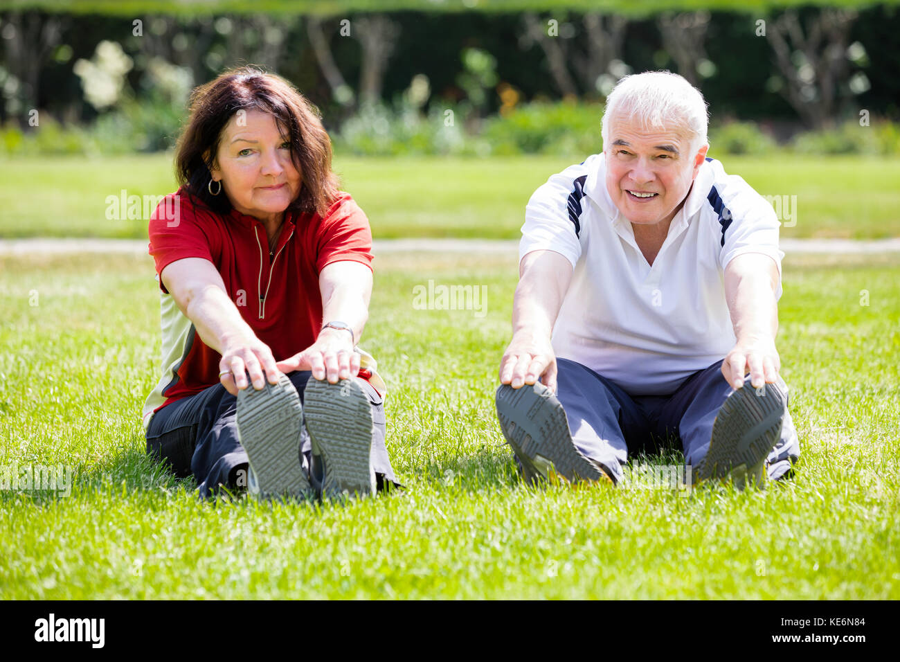 Anziana coppia senior facendo esercizio di allungamento in posizione di parcheggio Foto Stock