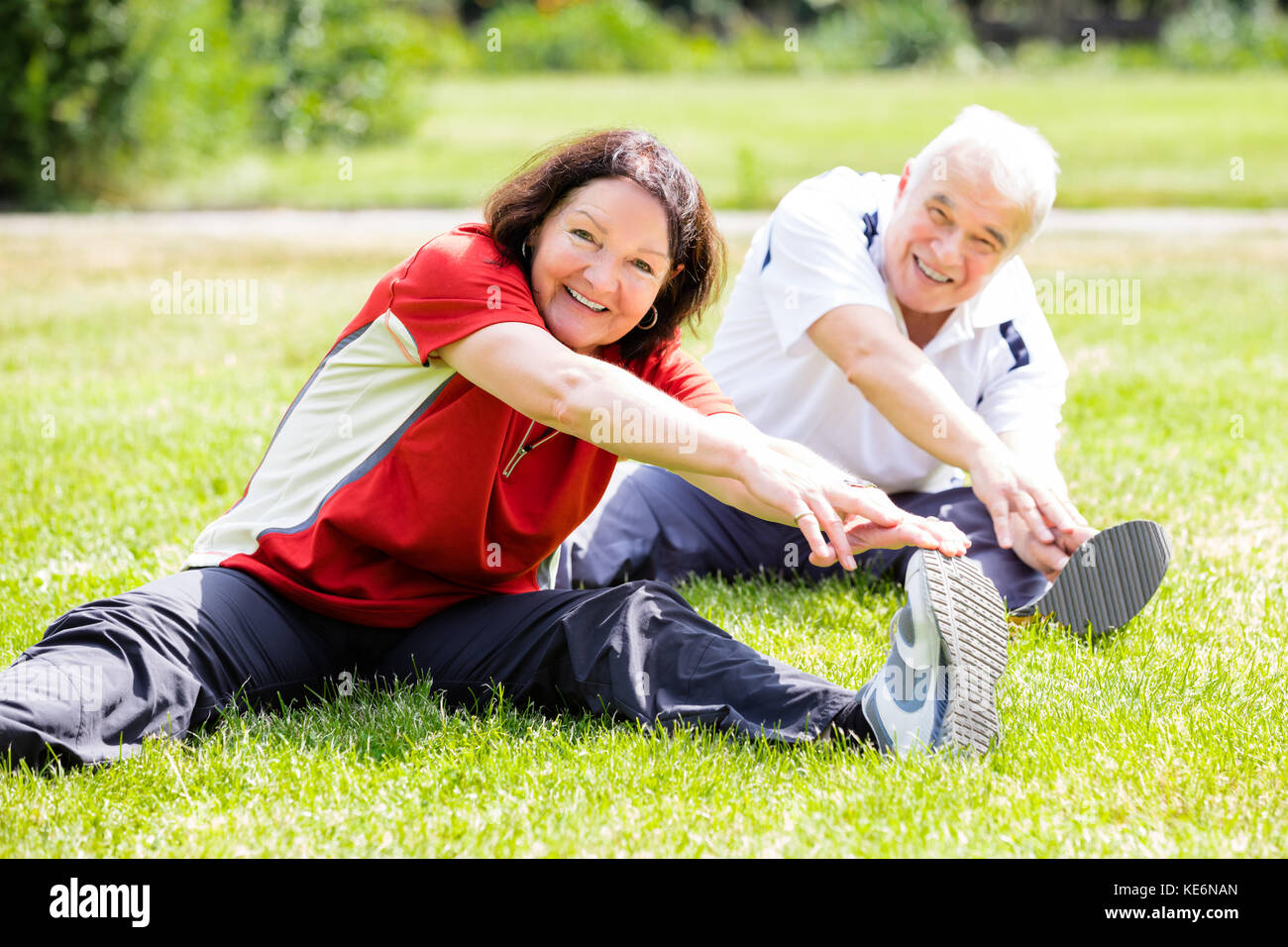 Sorridente coppia senior facendo esercizio di fitness in posizione di parcheggio Foto Stock