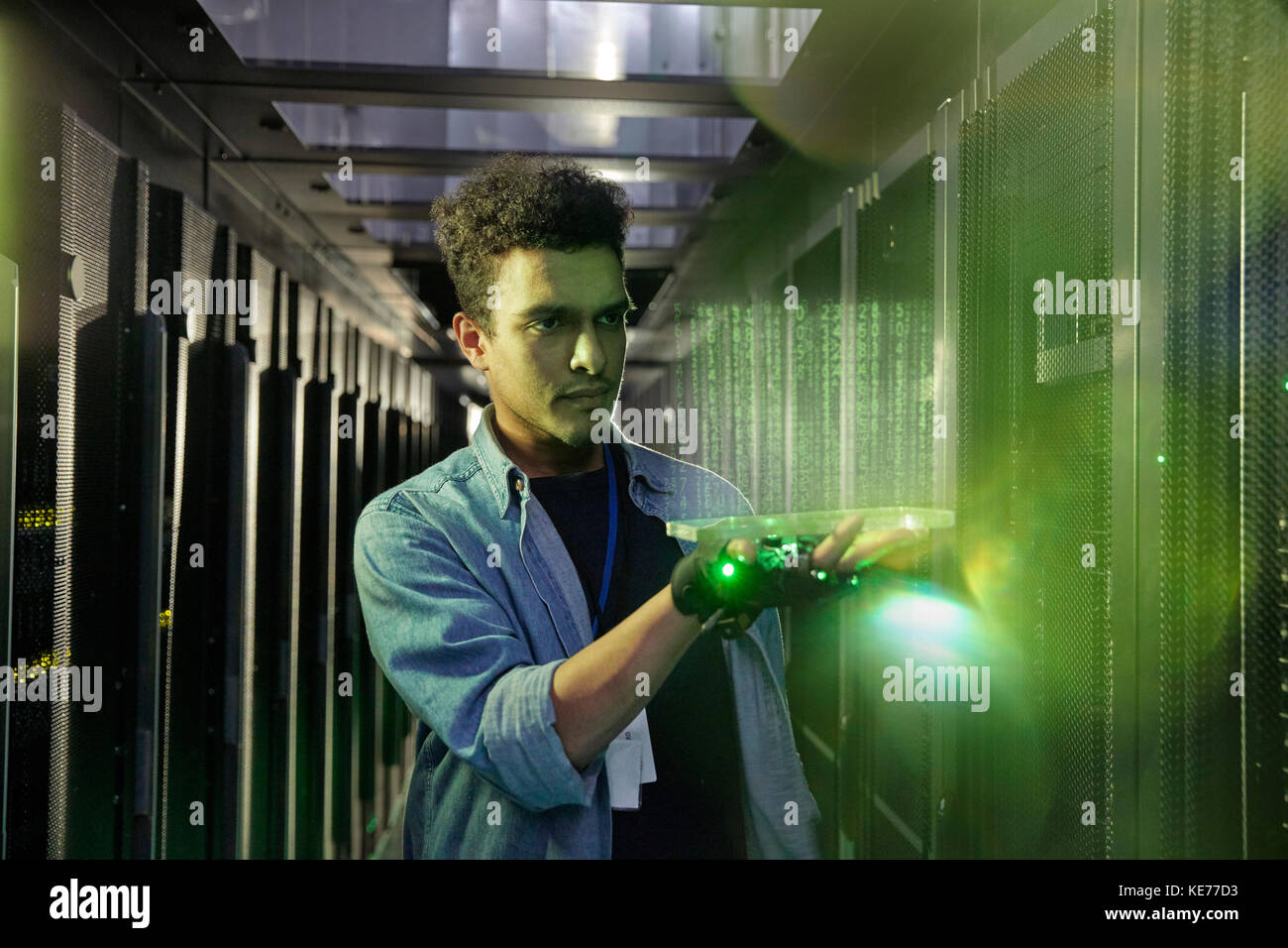 Tecnico IT di sesso maschile che detiene un tablet digitale futuristico e brillante nel server camera Foto Stock