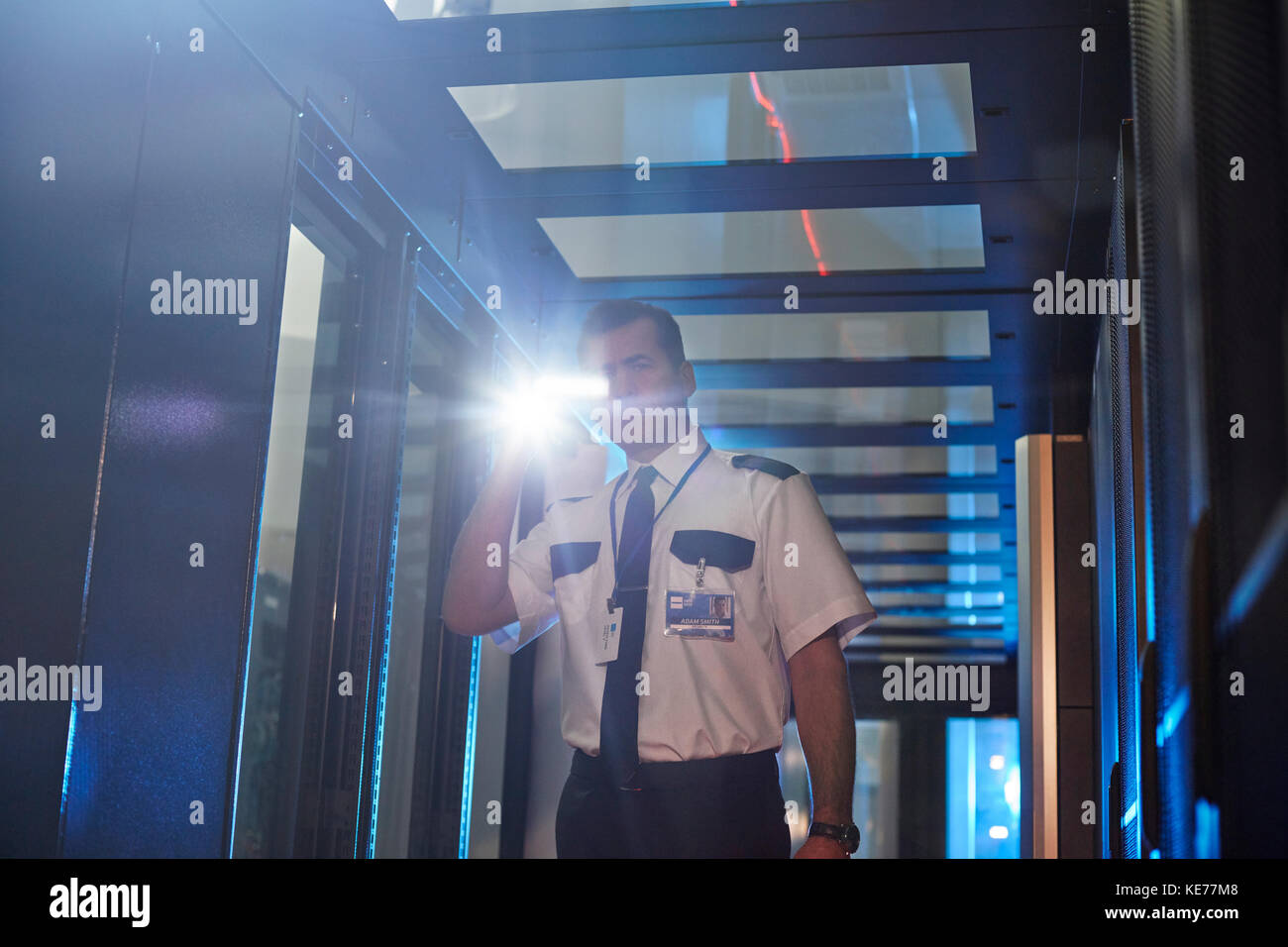 Guardia di sicurezza maschile con torcia nella sala server Foto Stock