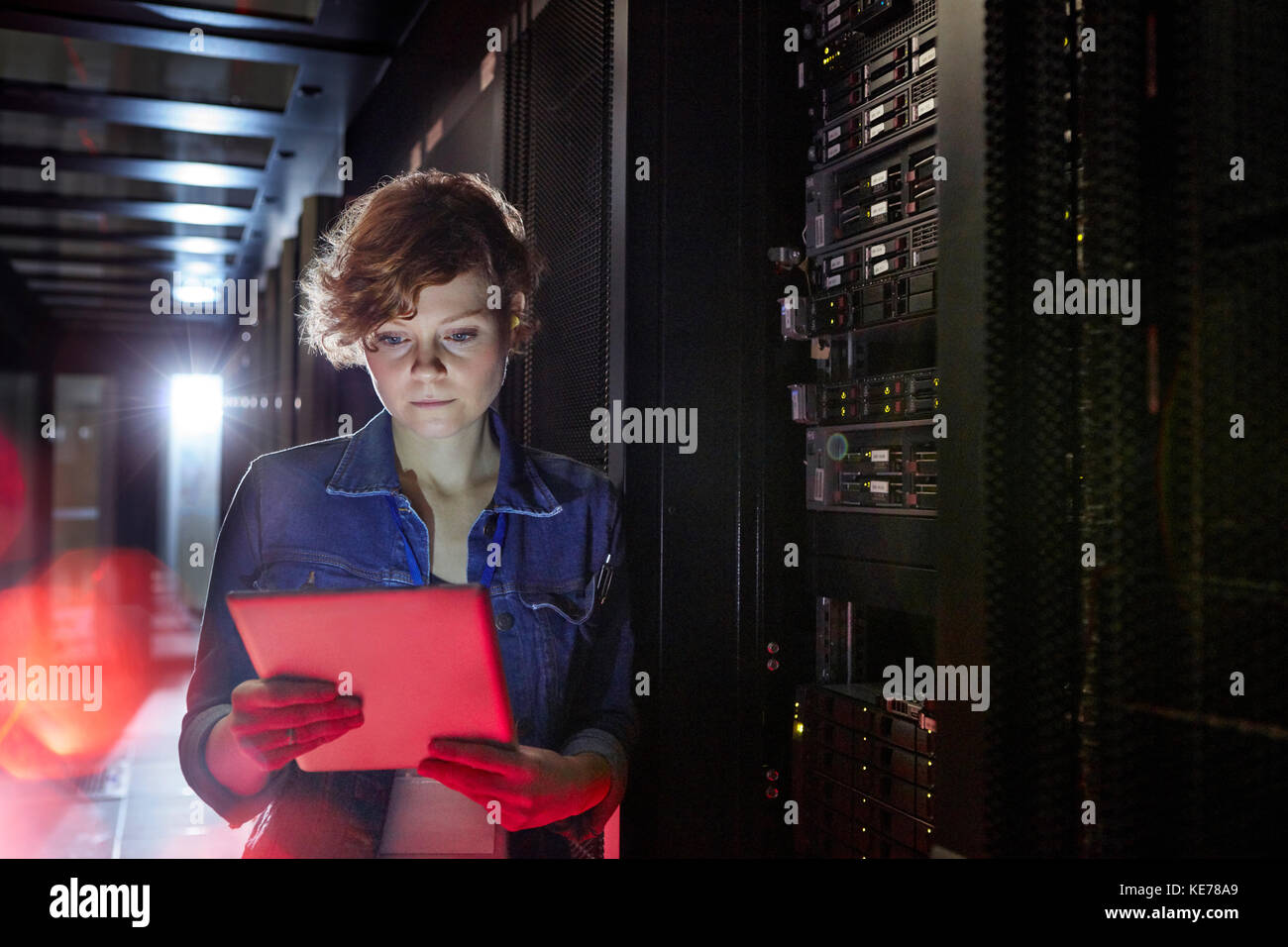 Femmina focalizzato tecnico IT con tavoletta digitale in sala server Foto Stock