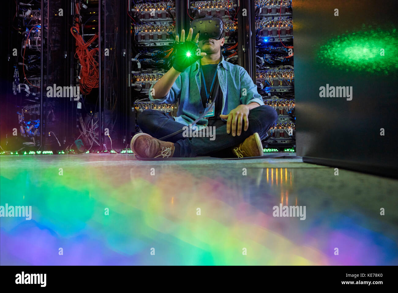 Programmatore di computer maschile che utilizza occhiali con simulatore di realtà virtuale al buio sala server Foto Stock