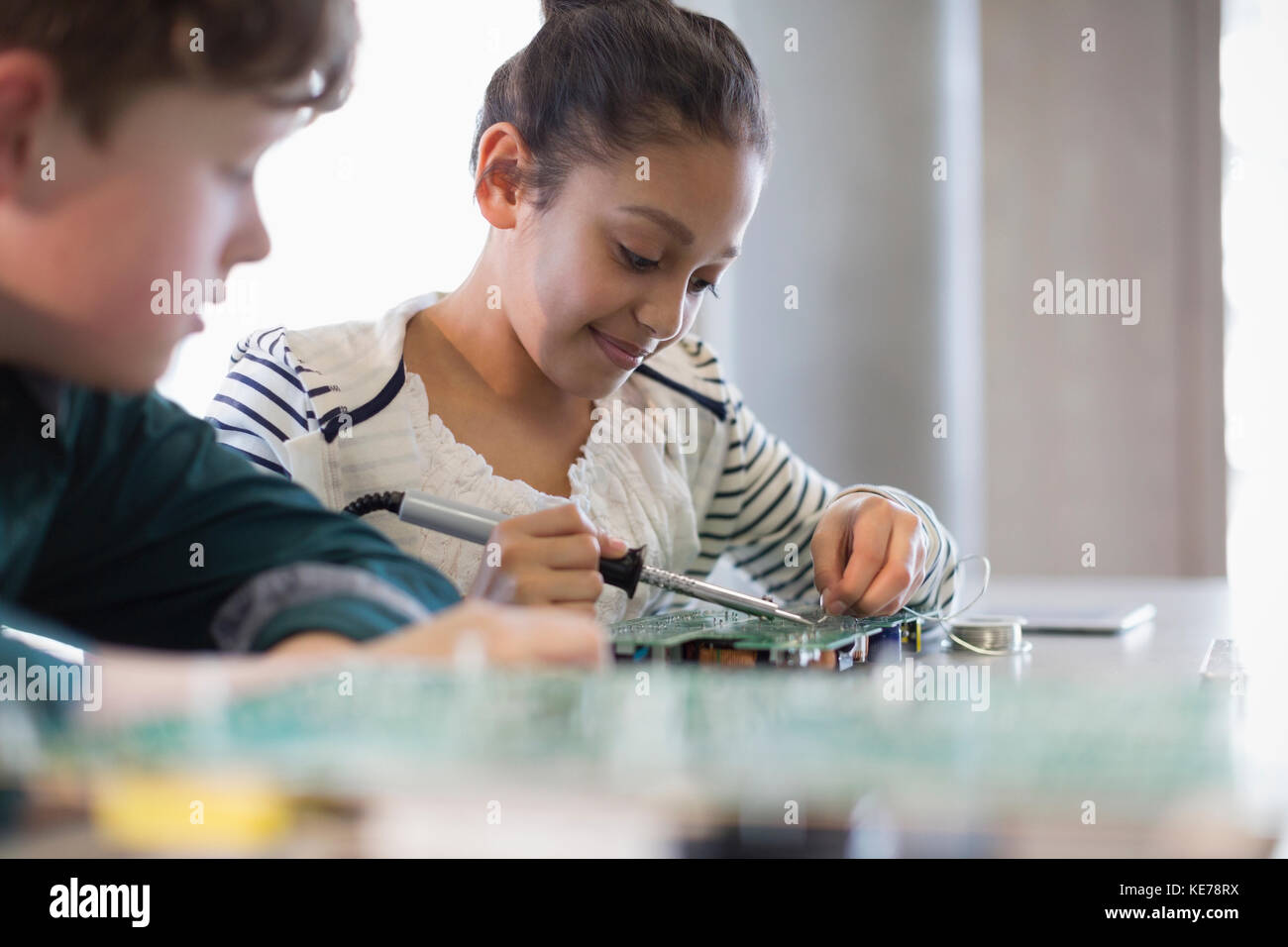 Gli studenti saldano la scheda a circuito stampato in classe Foto Stock