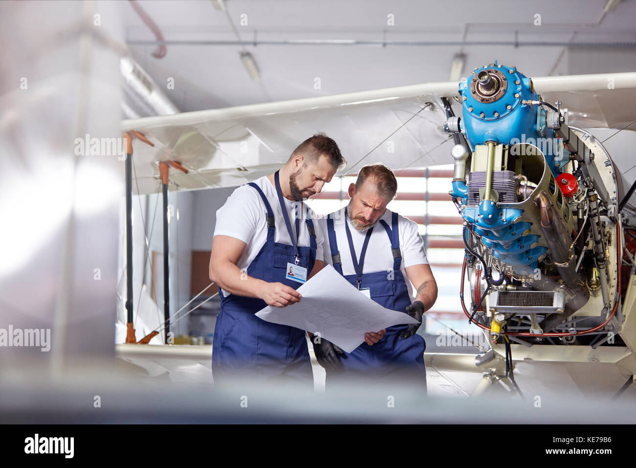 Meccanico ingegnere maschile che esamina i piani, riparando aereo in hangar Foto Stock