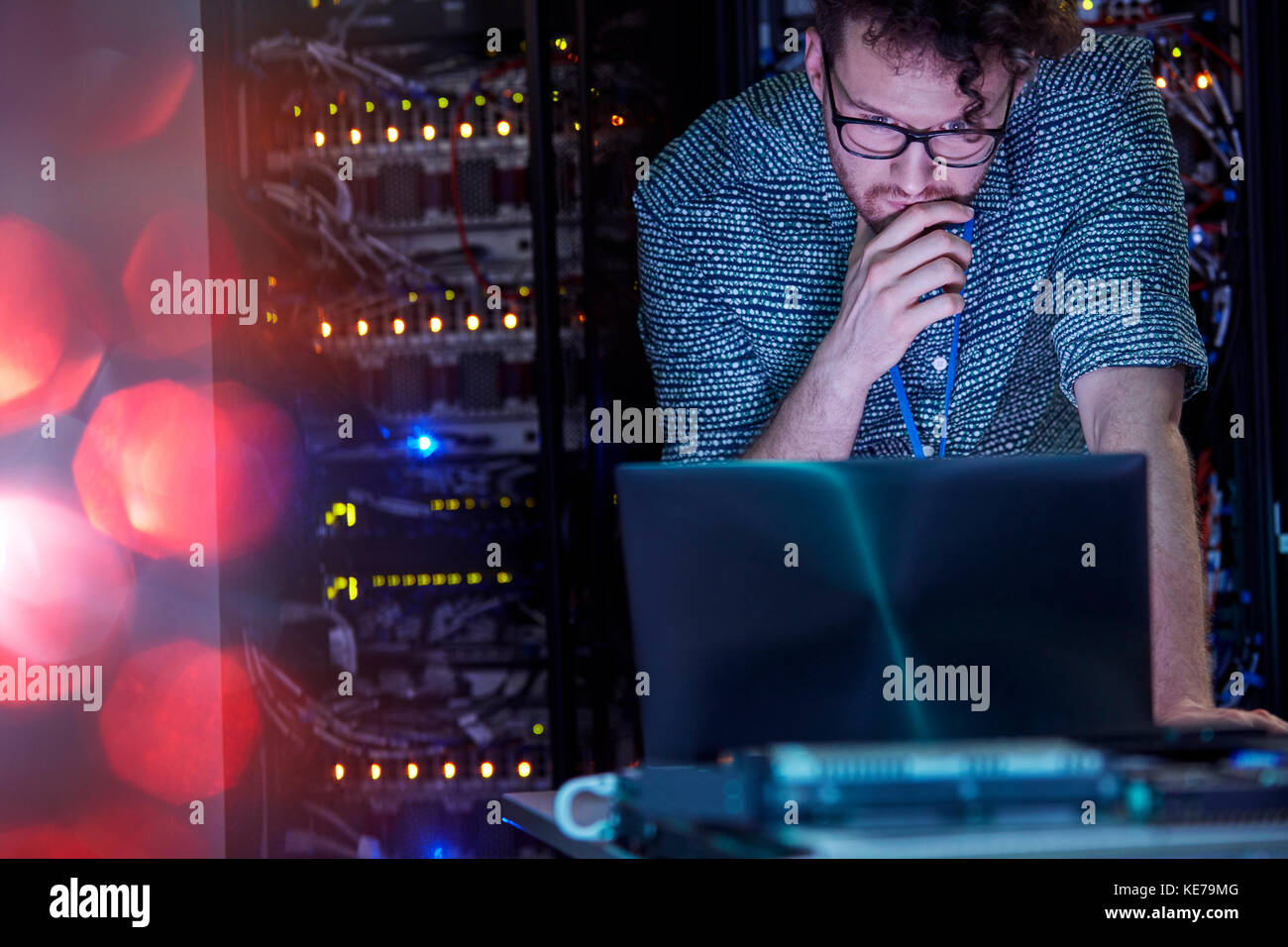 Tecnico IT maschile specializzato che lavora su un computer portatile in un server buio camera Foto Stock
