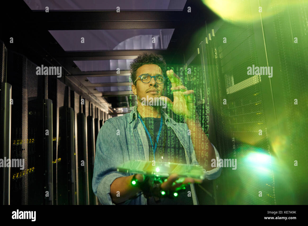 Tecnico IT maschile che utilizza un tablet digitale futuristico in un server buio camera Foto Stock