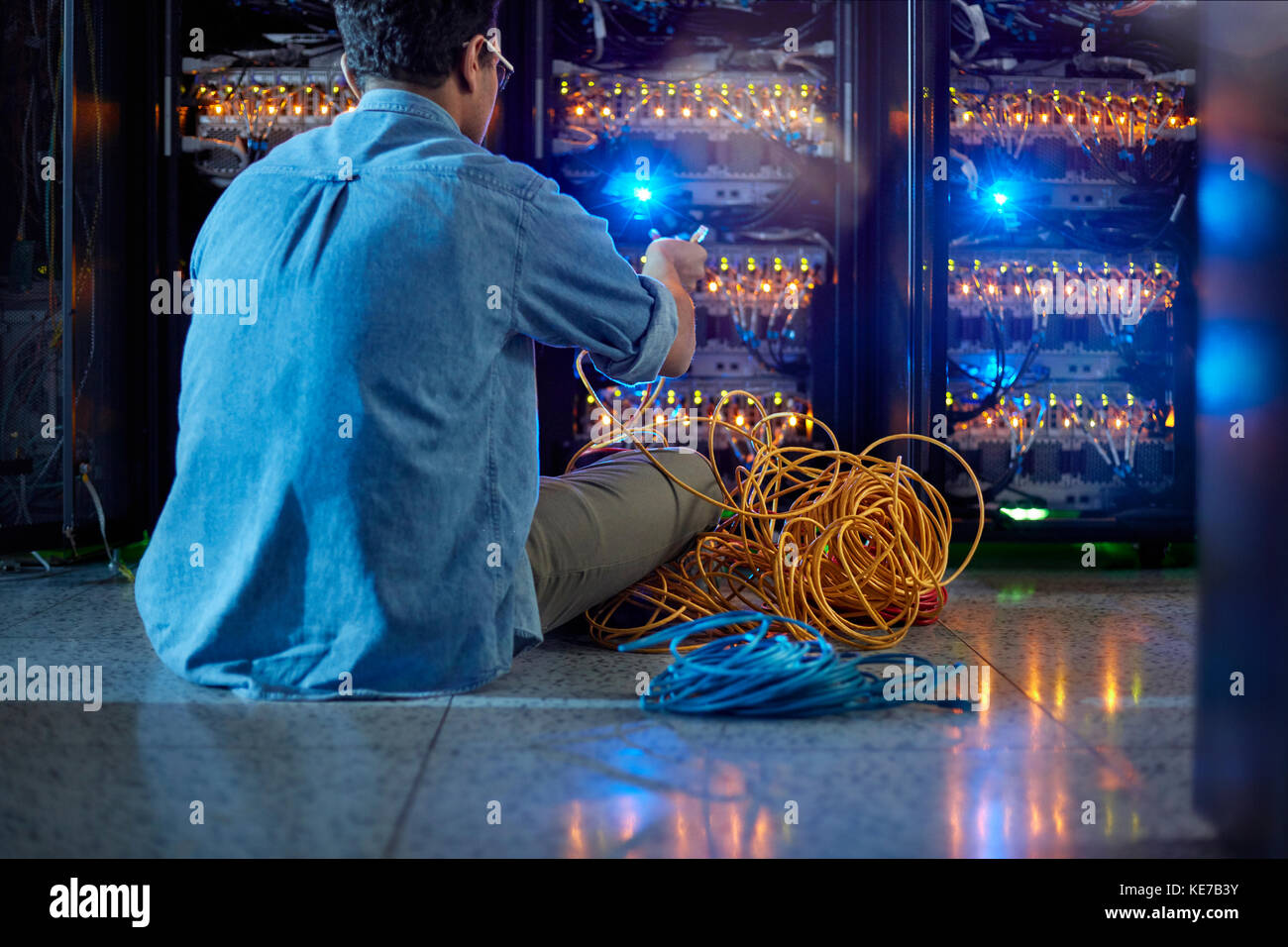 Tecnico IT maschile con cavi al pannello in un server scuro camera Foto Stock