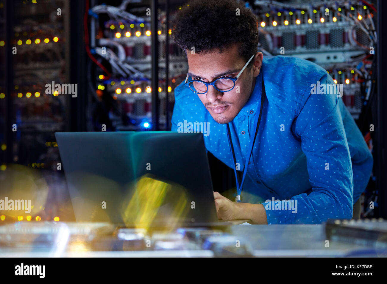 Tecnico IT maschile specializzato che lavora su un computer portatile in un server buio camera Foto Stock