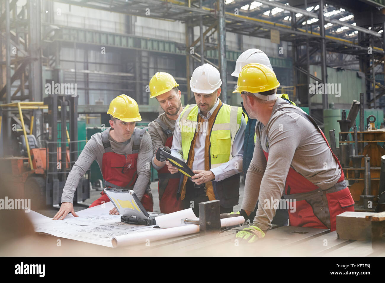 Caposquadra maschile, ingegneri e lavoratori che si riunano in fabbrica con il tablet digitale Foto Stock