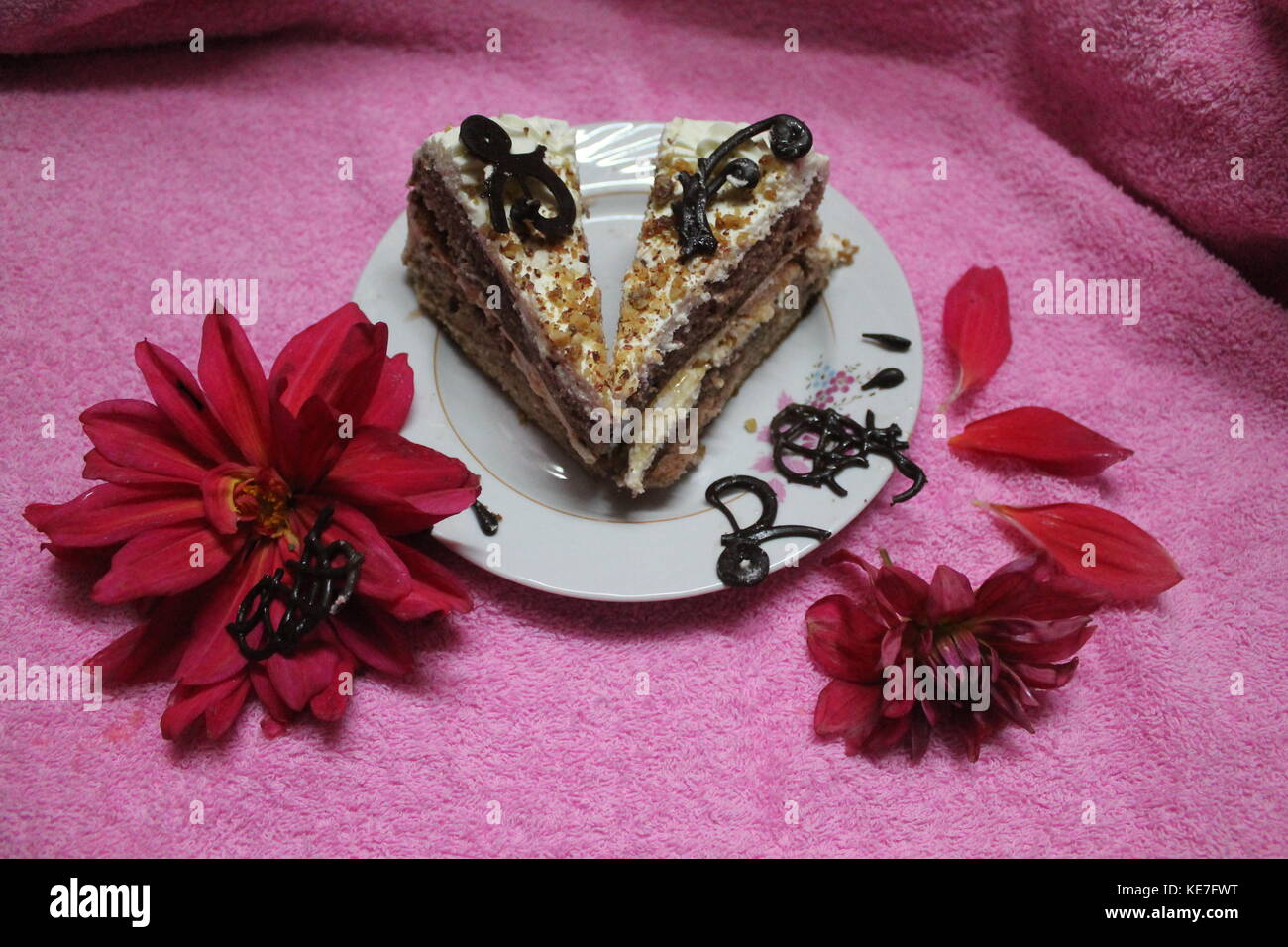 Pezzi di crema di cioccolato torta sulla piastra decorate in rosso sbocciano i fiori Foto Stock