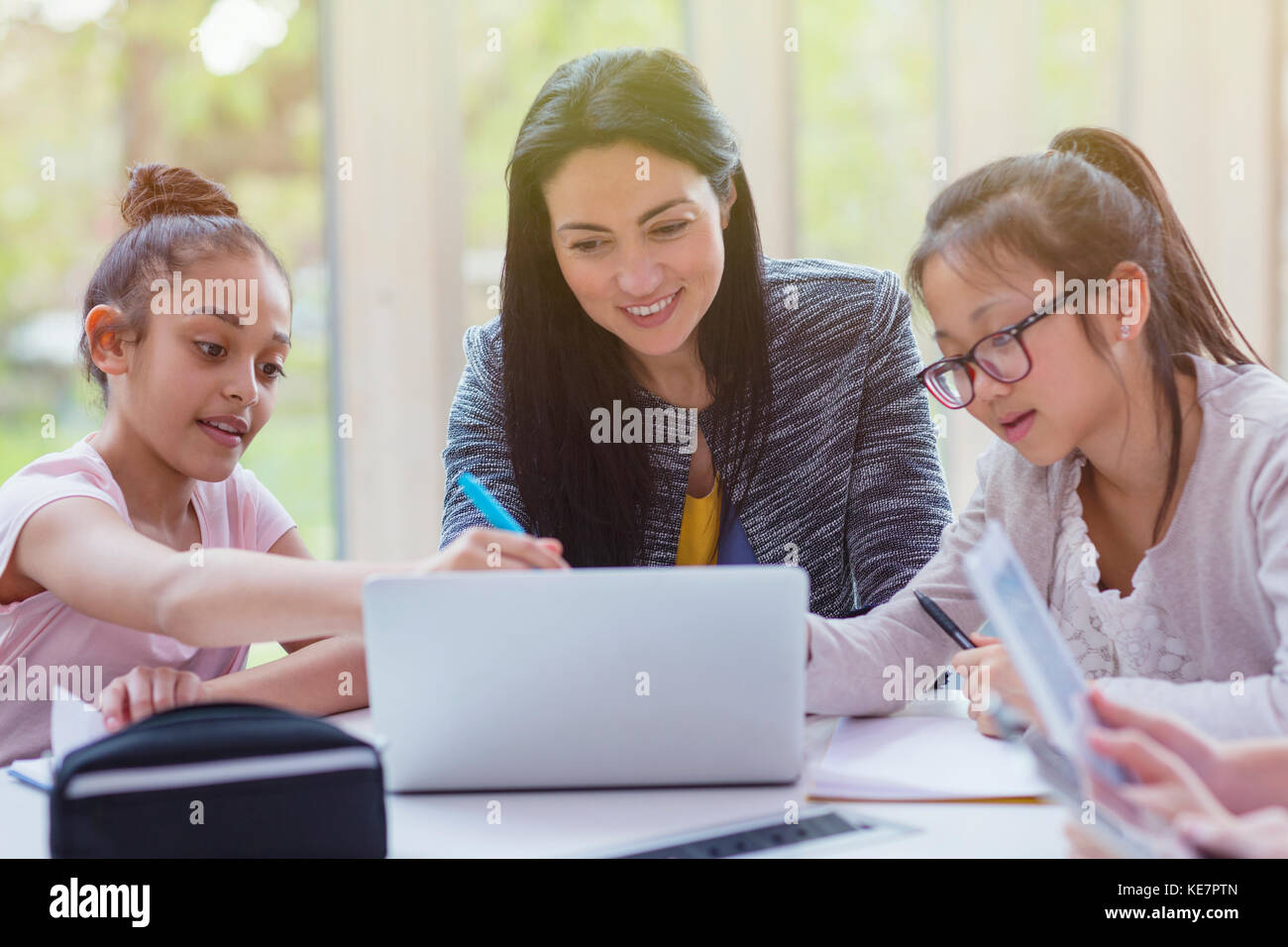 Insegnante femminile e studentesse che ricercano al laptop in biblioteca Foto Stock