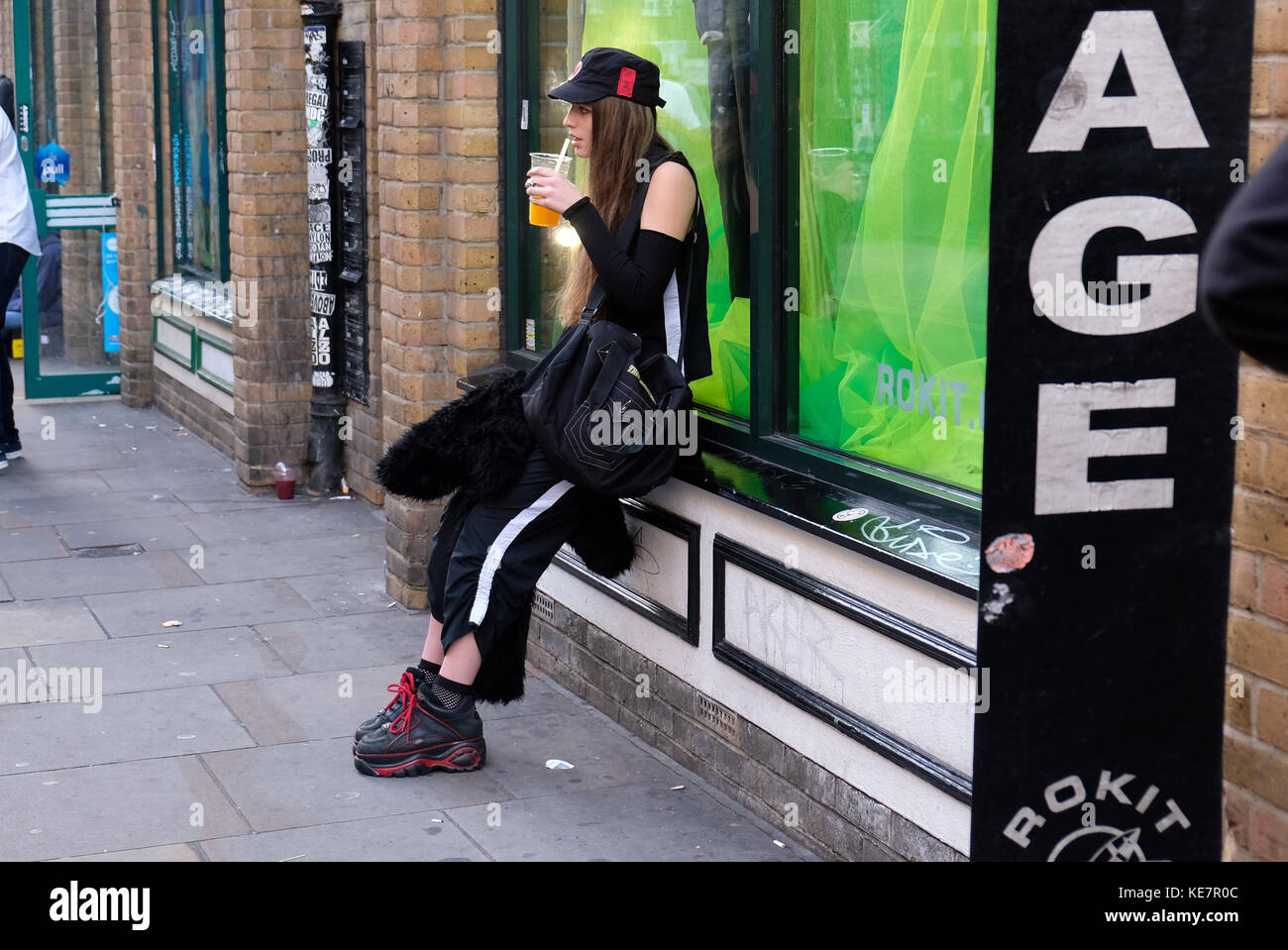 Ragazza alla moda sorseggiando drink Shoreditch Foto Stock