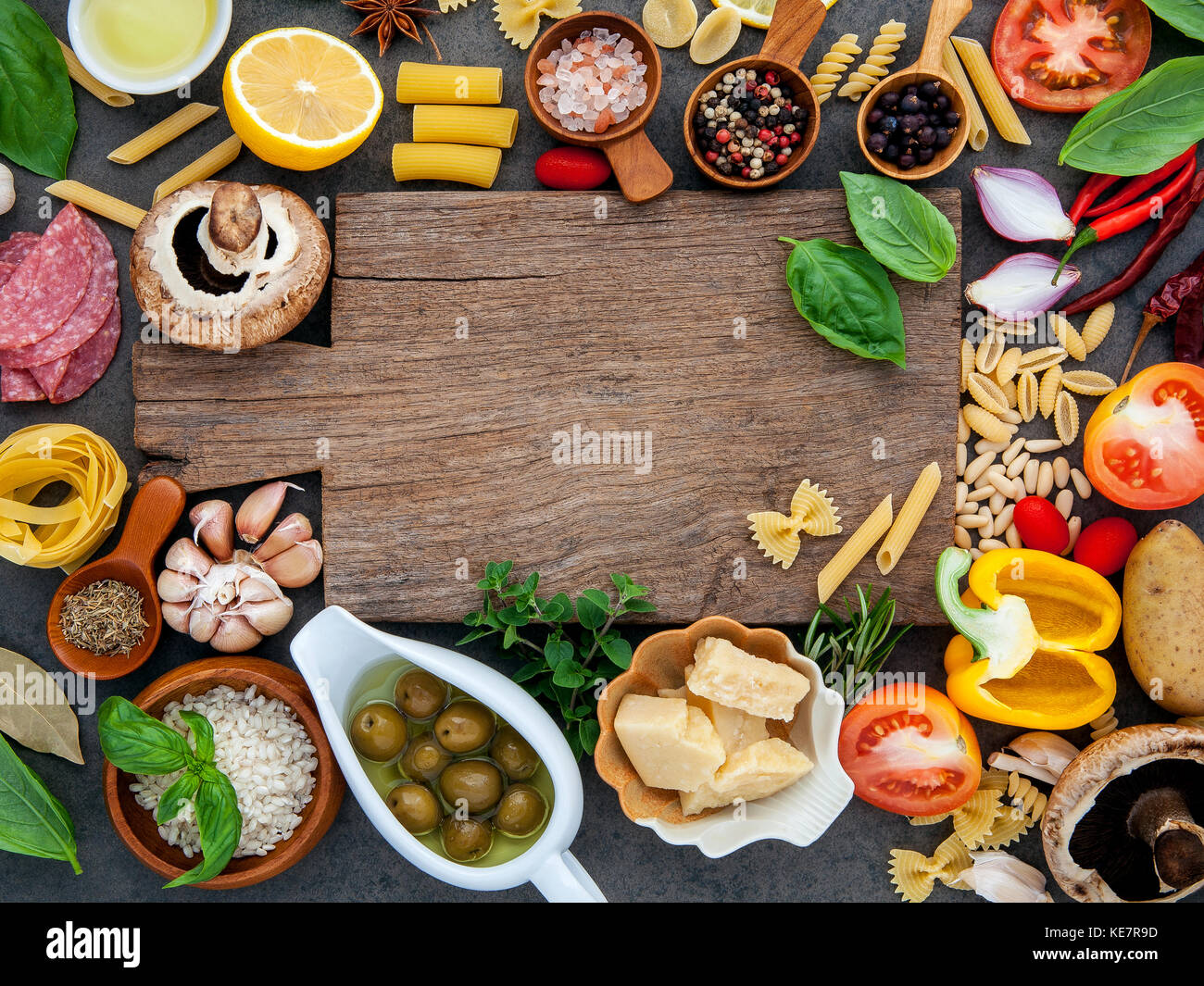 Il cibo italiano di cottura Ingredienti in pietra scura lo sfondo con il bordo di taglio piatto e laici copia spazio. Foto Stock