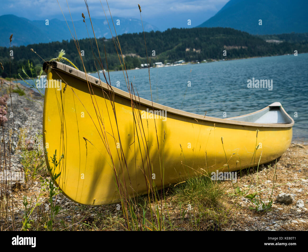 Un giallo brillante canoe sulla riva del lago Slocan; Nuovo Denver, British Columbia, Canada Foto Stock
