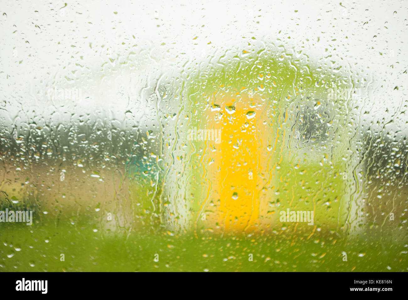 Un piccolo edificio verde con giallo porta e di una finestra vista attraverso una finestra bagnata con gocce di pioggia; Terranova, Canada Foto Stock