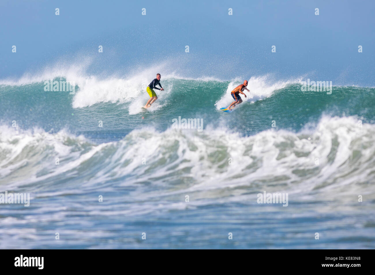 Una coppia di surfisti cavalcare un onda al Pelican Beach sull'Oceano Atlantico; Satellite Beach, Florida, Stati Uniti d'America Foto Stock