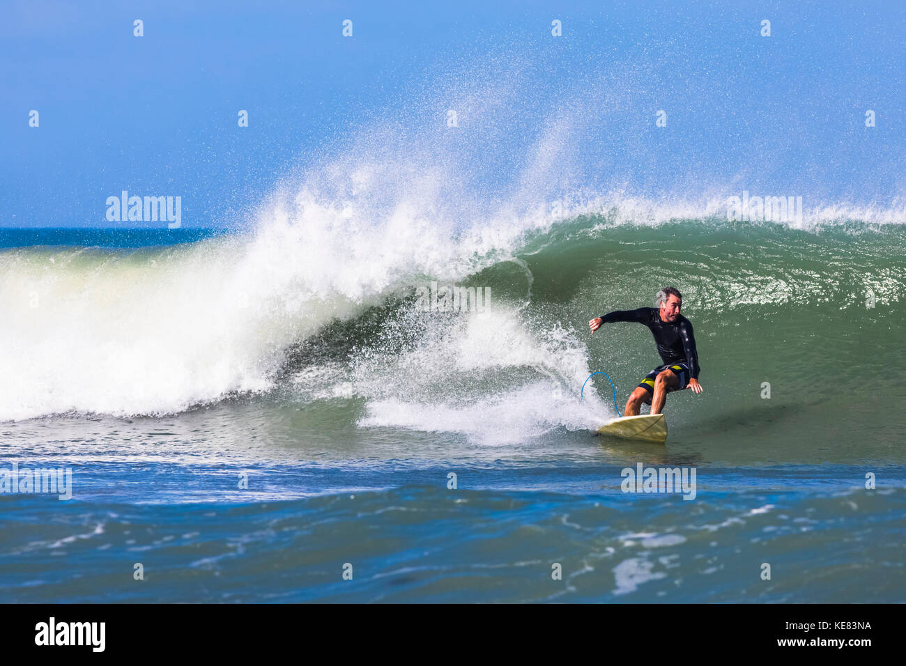 Un surfista cavalca un onda al Pelican Beach sull'oceano atlantico in Florida; Satellite Beach, Florida, Stati Uniti d'America Foto Stock