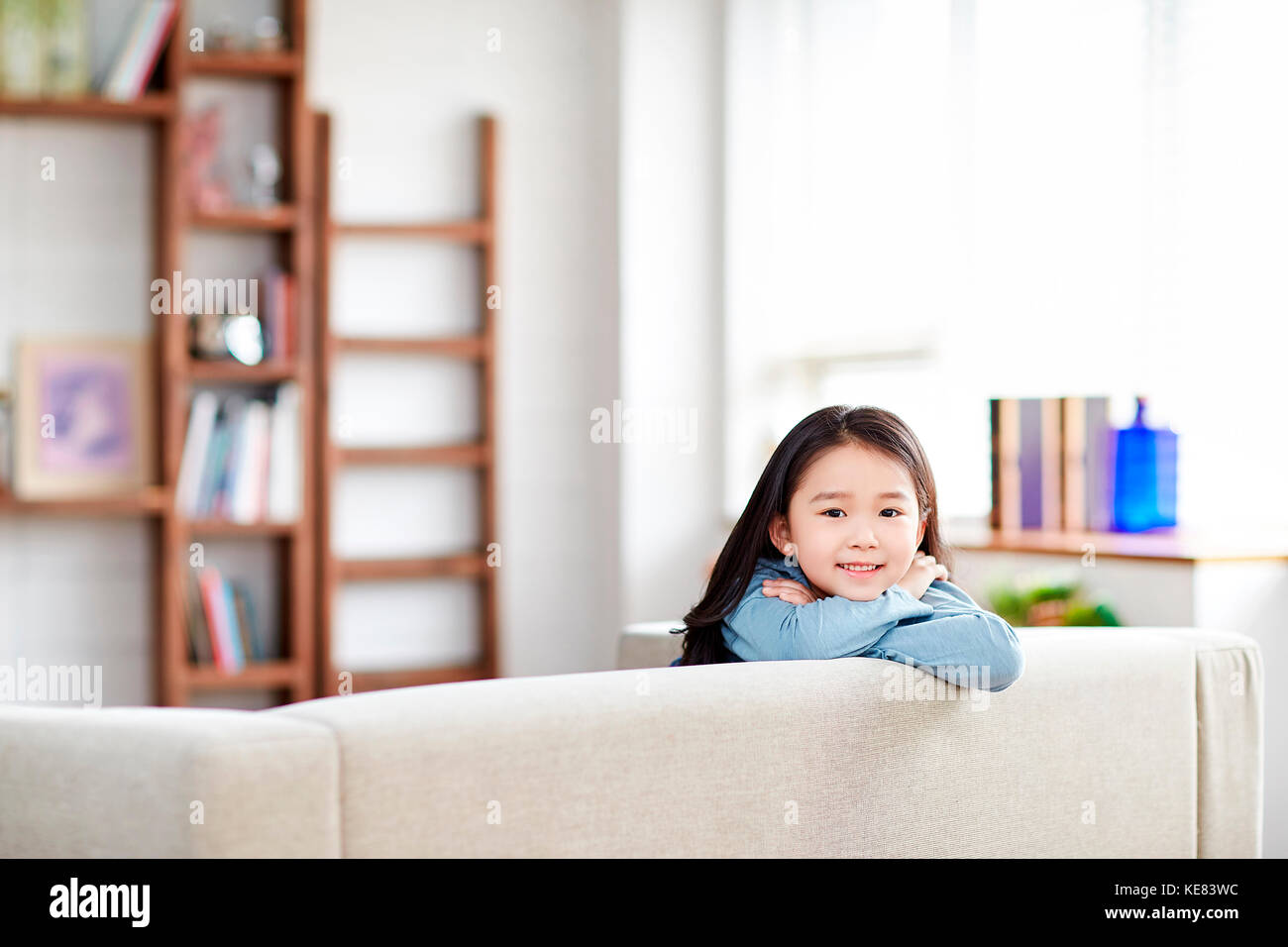 Ragazza sorridente in posa al divano Foto Stock