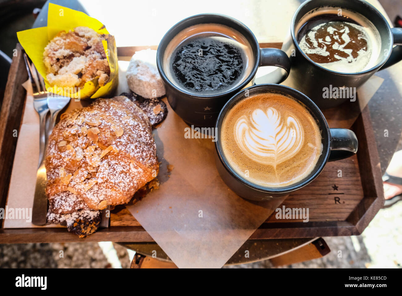 Tre tazze di caffè gourmet e pezzi di pasticceria in un vassoio Foto Stock