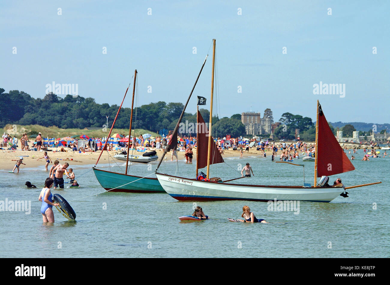 Le famiglie di balneazione e sul Studland Bay beach, Branksea castello su Brownsea Island in background, Dorset, Inghilterra Foto Stock