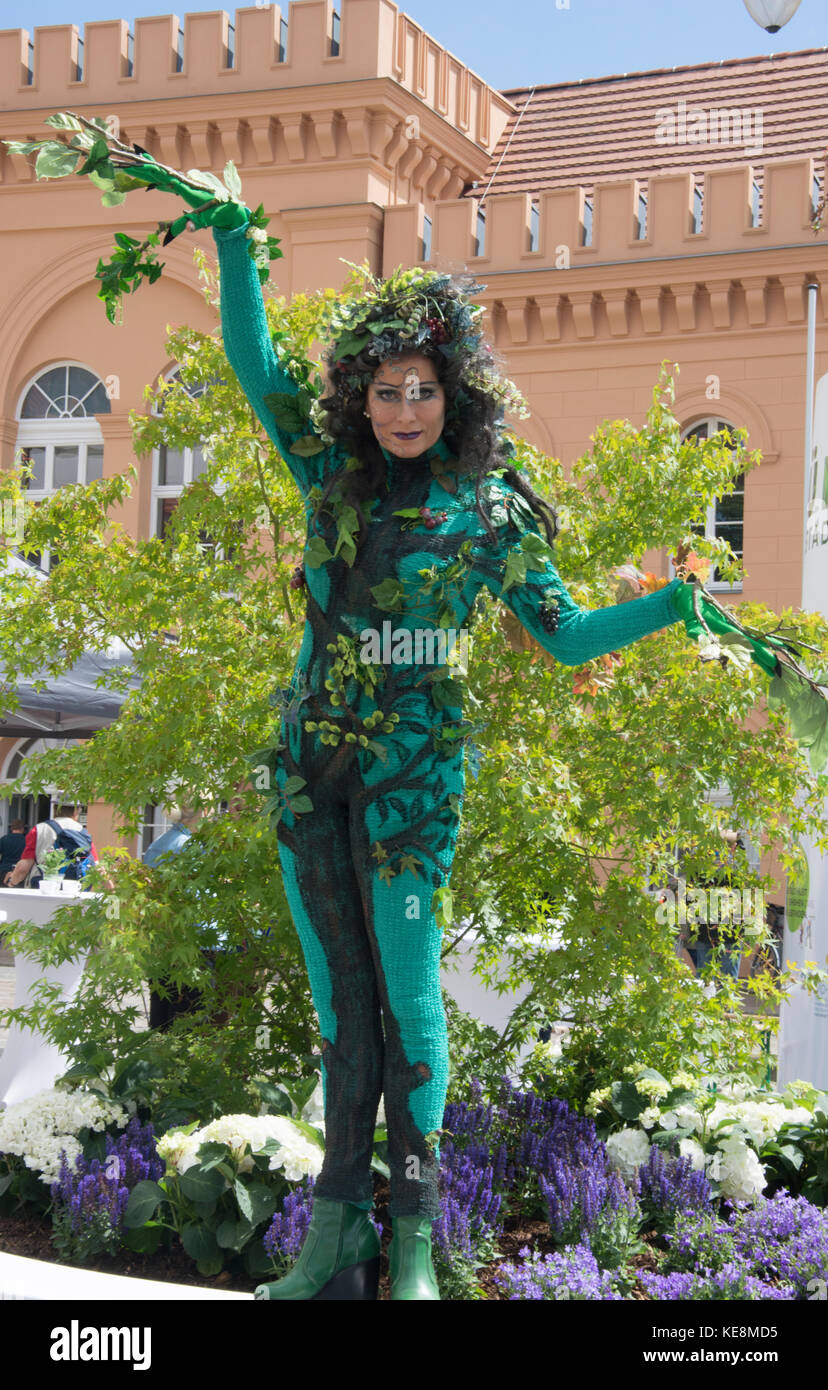 Donna in costume come un verde sprite esegue in Am Markt, la piazza del mercato di Schwerin, Germania, per promuovere l'energia verde iniziative Foto Stock