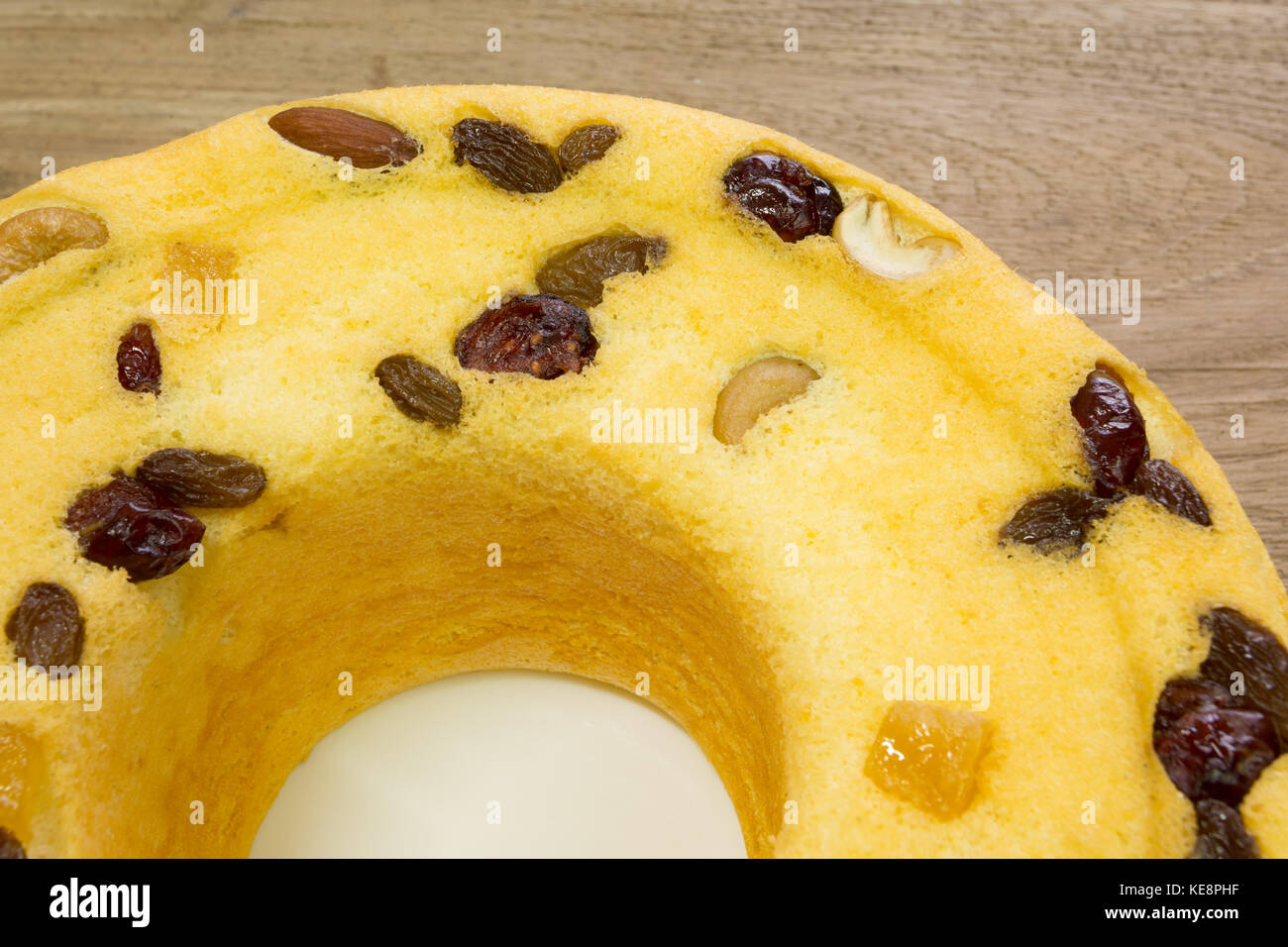 Torta di cotone, miscela di frutti di mandorla, noci di anacardi, mirtilli rossi, mango secchi, uvetta verde, su piatto bianco, pronto a mangiare, su un rustico tavolo di legno Foto Stock