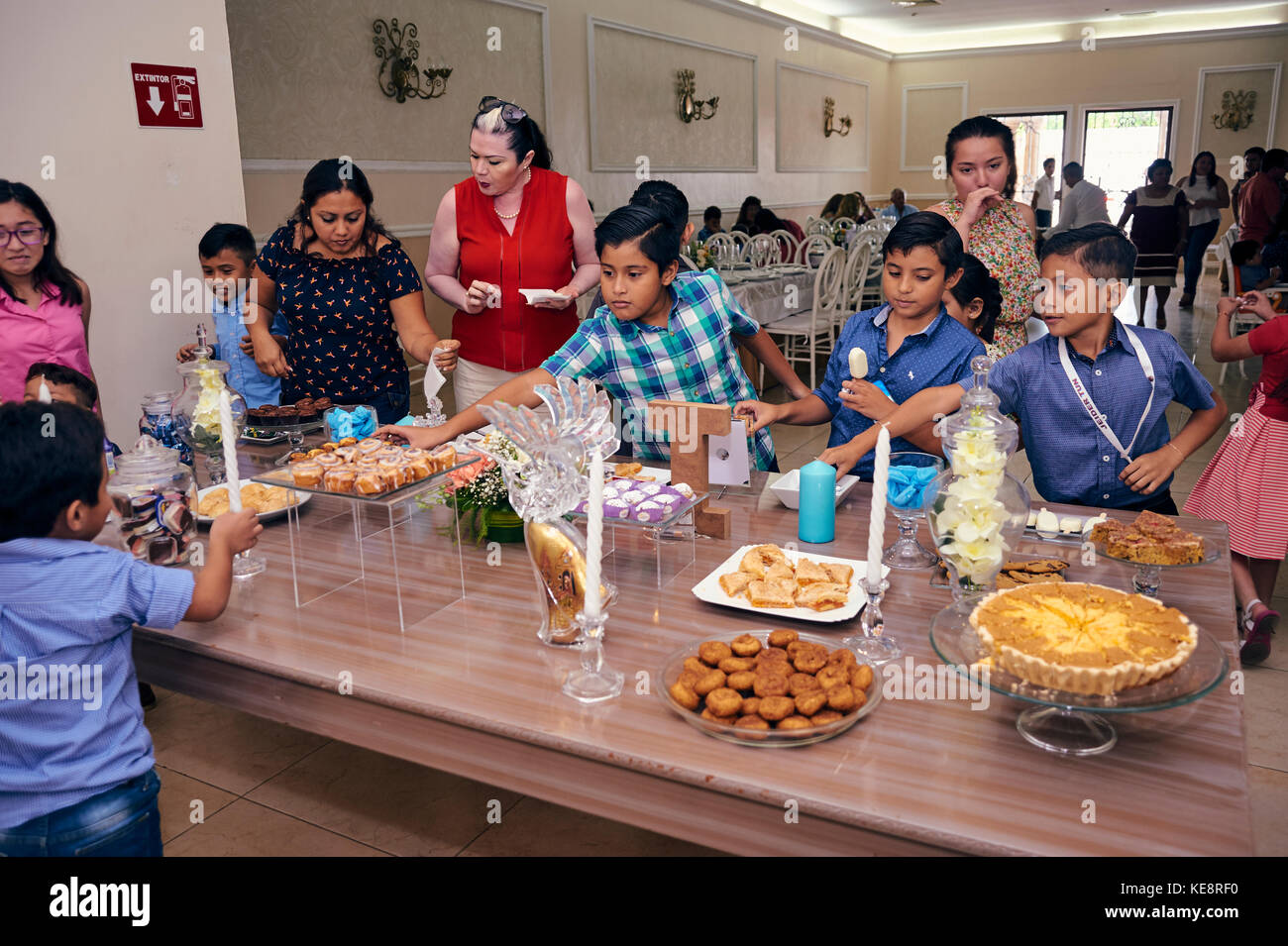 I bambini si precipitavano al tavolo dei dolci al battesimo Foto Stock