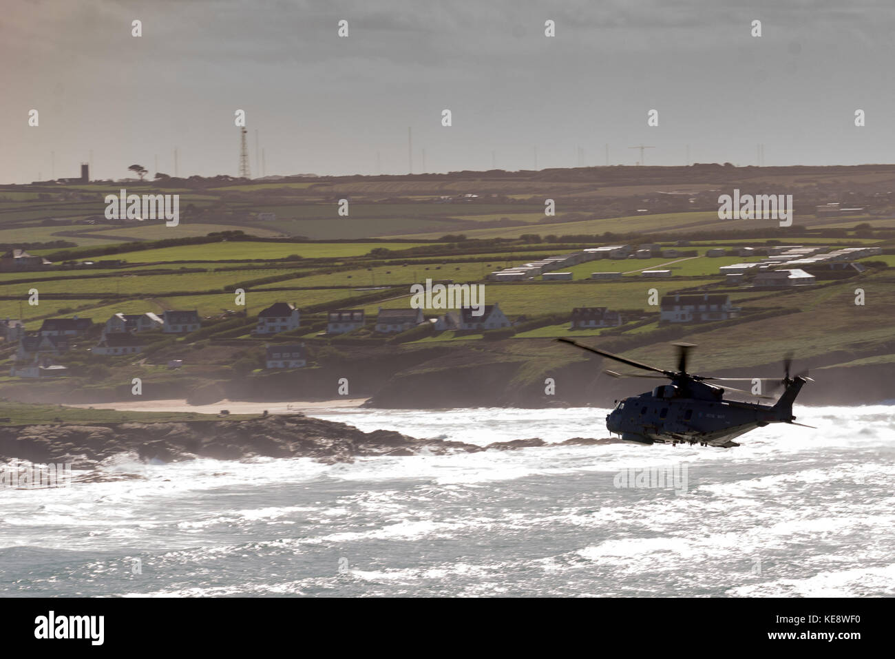 Elicottero in silhouette capi attraverso navigare verso una spiaggia e approdo Foto Stock