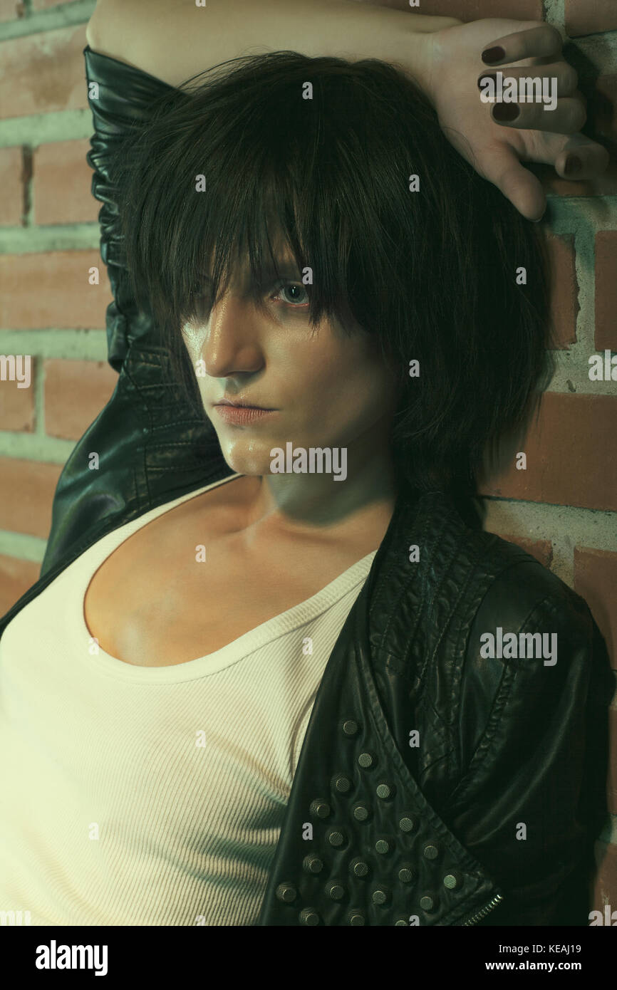 L'androginia modello femminile di eroina chic stile vicino a un muro di mattoni. vecchio stile immagine oscurata Foto Stock