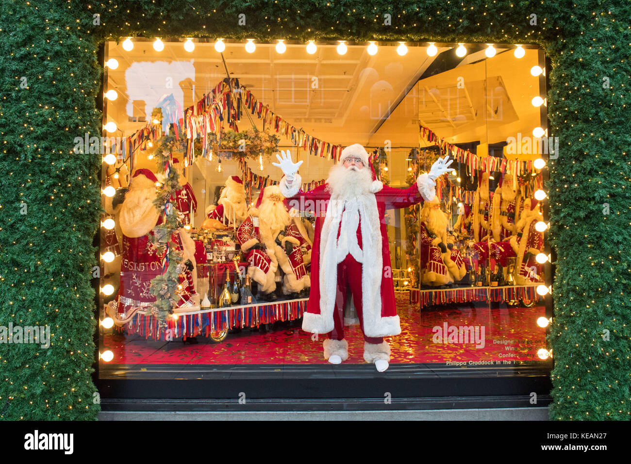 Un attore vestito da padre Natale all'interno di una vetrina di Natale, a tema come con amore da, che è una celebrazione delle città Selfridges chiama a casa, presso il grande magazzino Selfridges a Oxford Street, Londra. Foto Stock