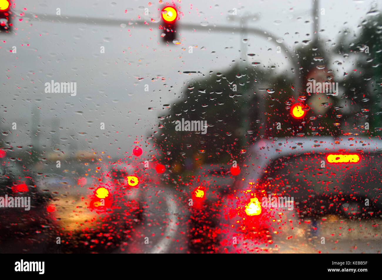 Gocce d'acqua sul vetro auto. sfocatura bokeh di fondo e le luci di strada dietro. Foto Stock