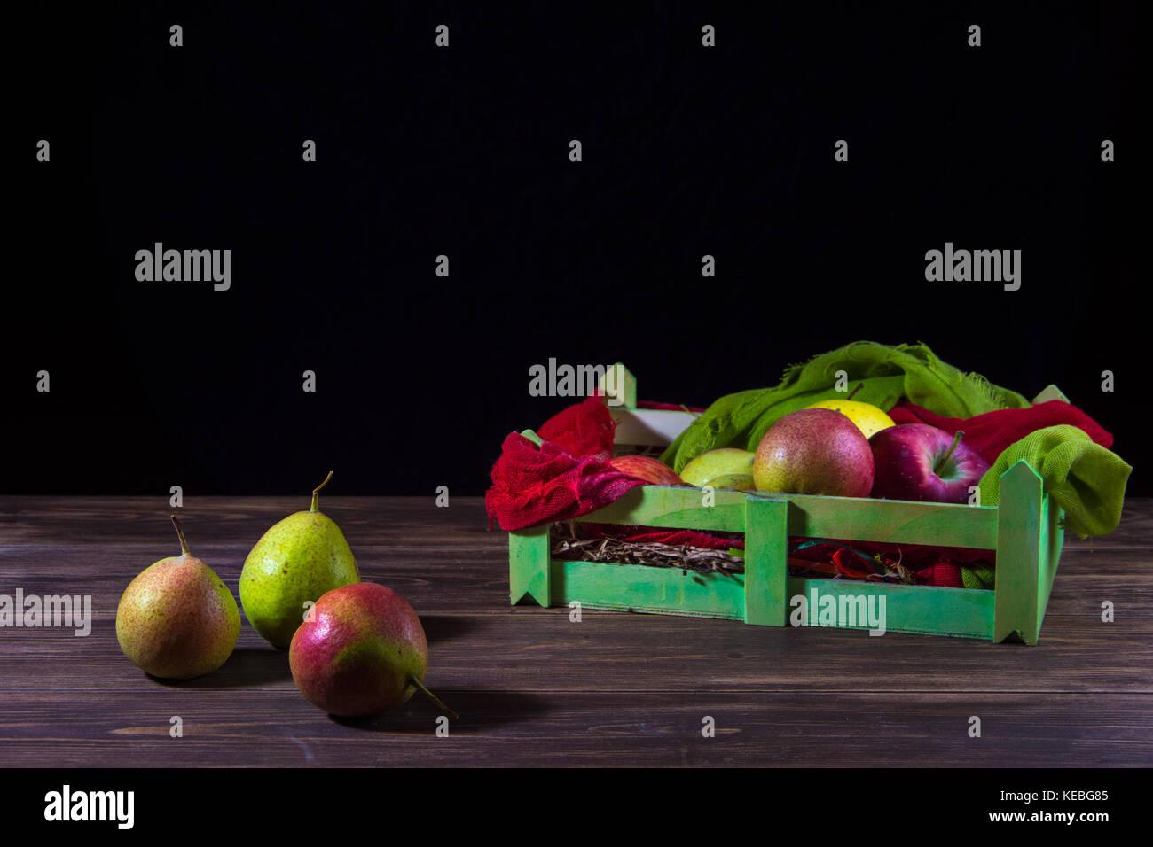 Scatola di frutta con pere selvatiche isolato sul tavolo di legno e uno sfondo scuro. Foto Stock