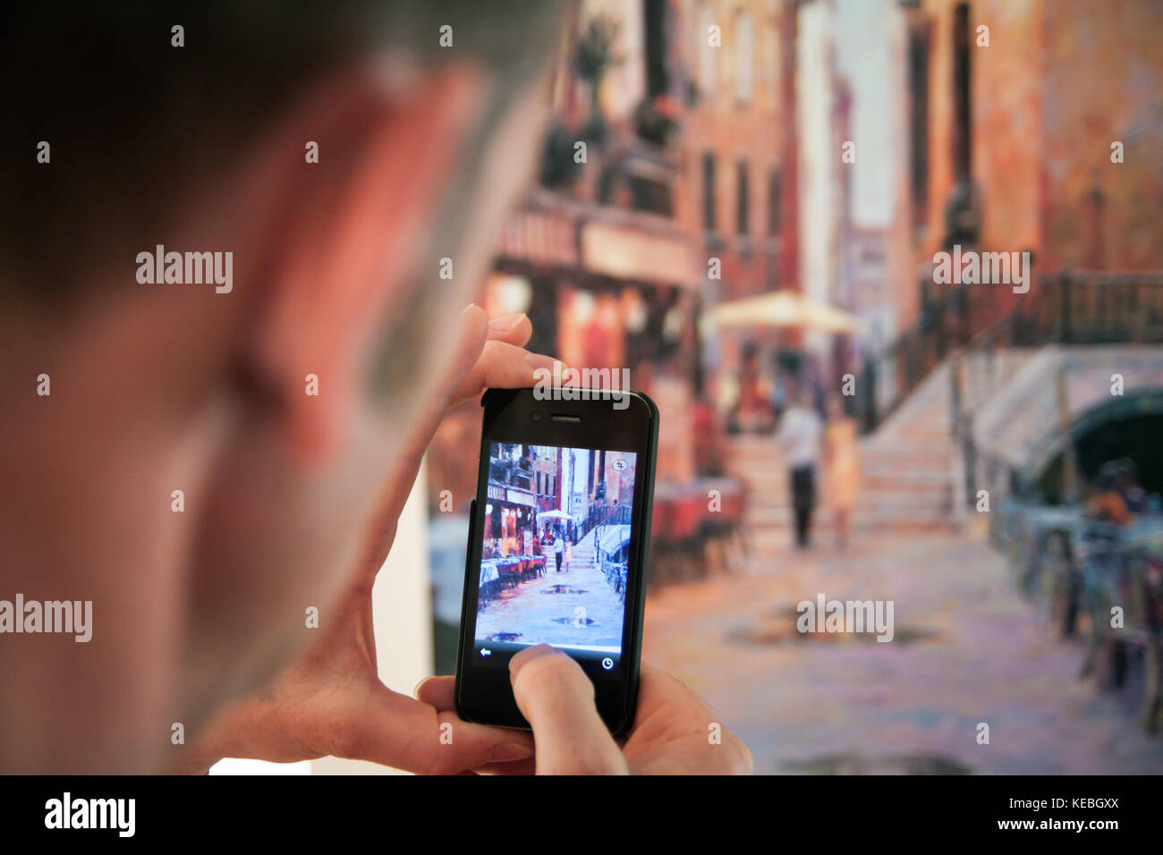 Trama entro una cornice. Un uomo prende una foto di una foto con il suo smartphone. Foto Stock
