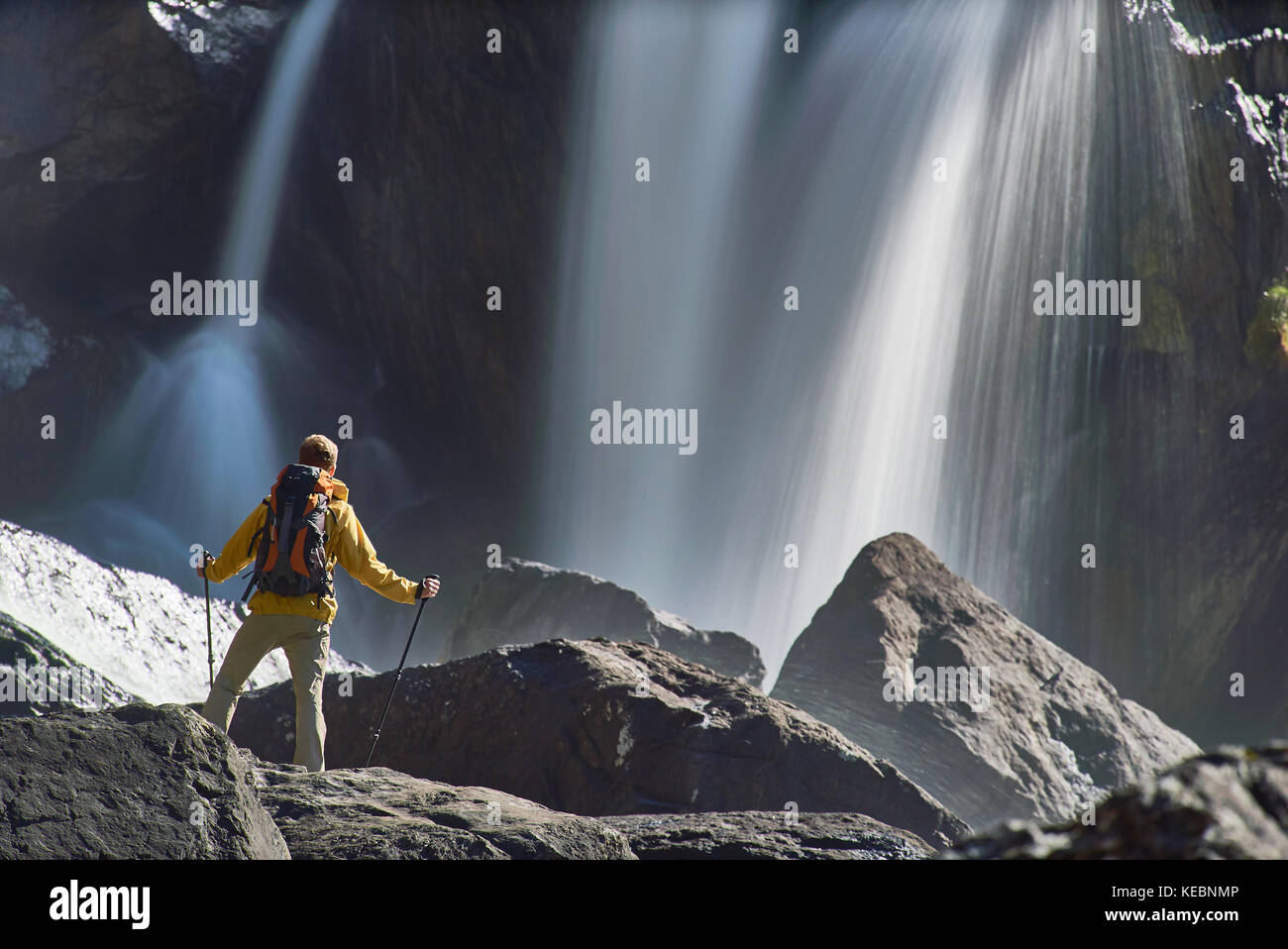 Escursionismo uomo con zaino guardando a cascata in bella estate natura paesaggio. ritratto del maschio adulto torna in piedi all'aperto. Foto Stock