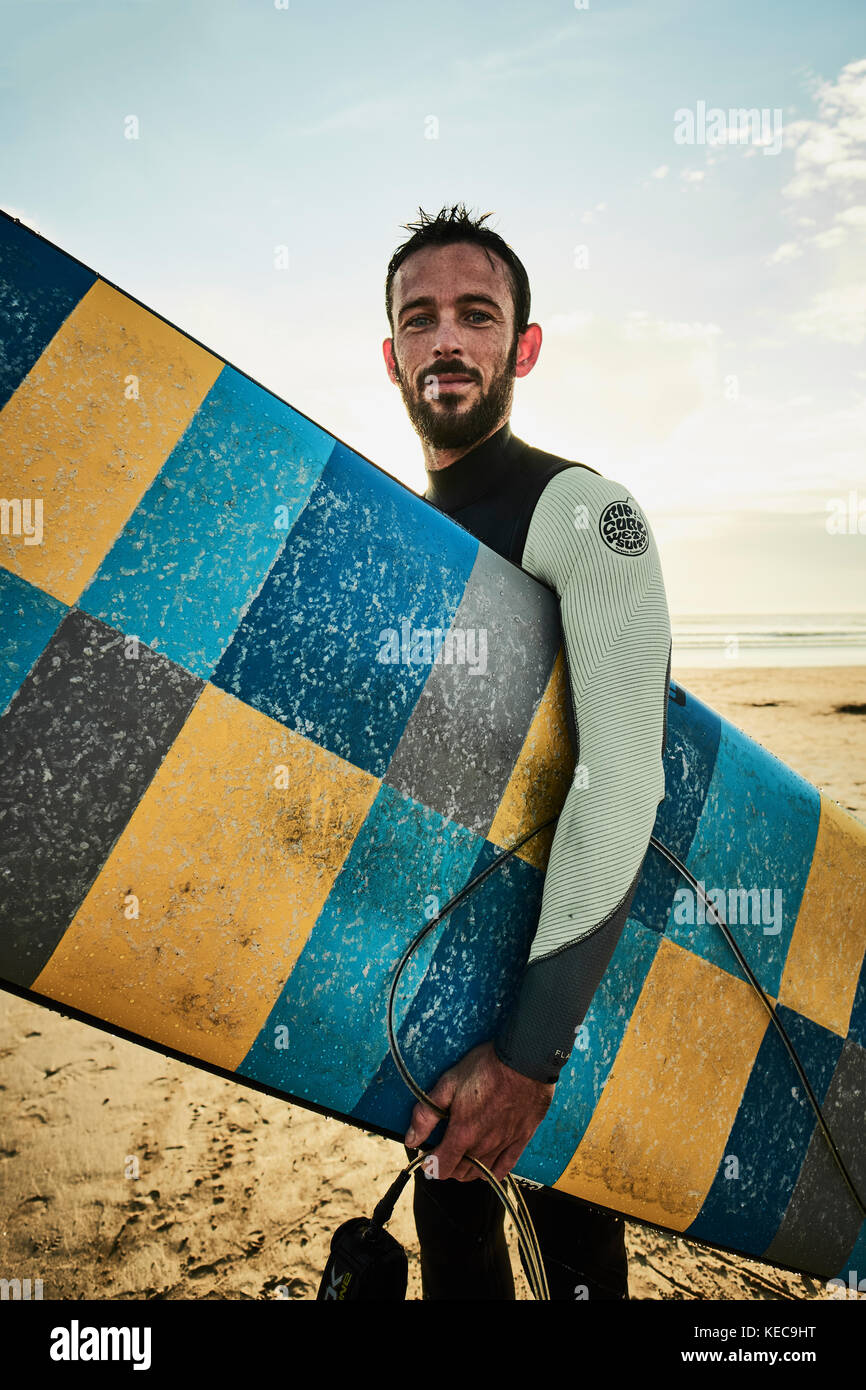 Uno stile di vita all'aperto ritratto di un surfista con la sua tavola da surf in spiaggia. Foto Stock