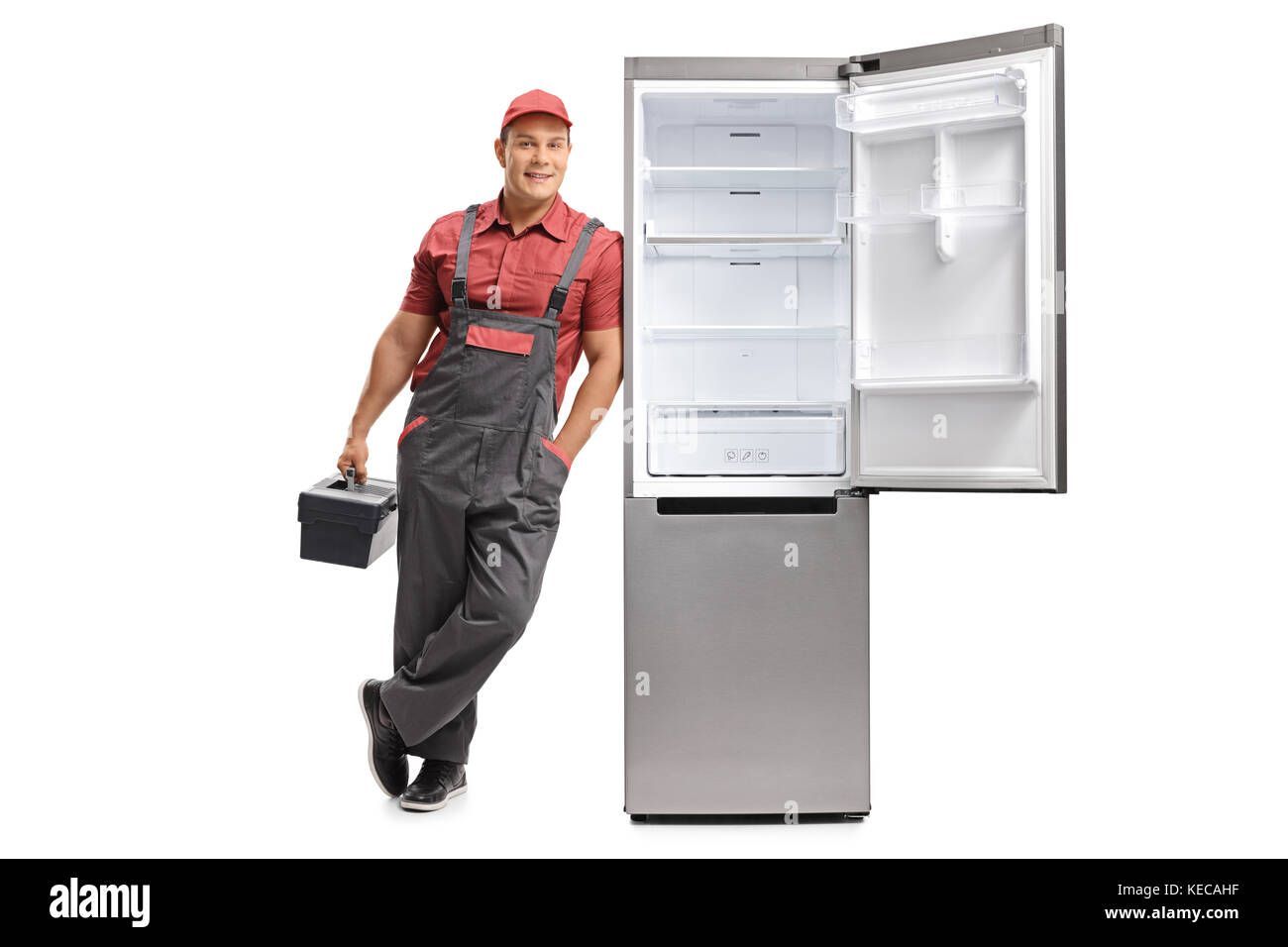 A piena lunghezza Ritratto di un aggiustatore con una toolbox appoggiata contro un frigo aperta isolata su sfondo bianco Foto Stock