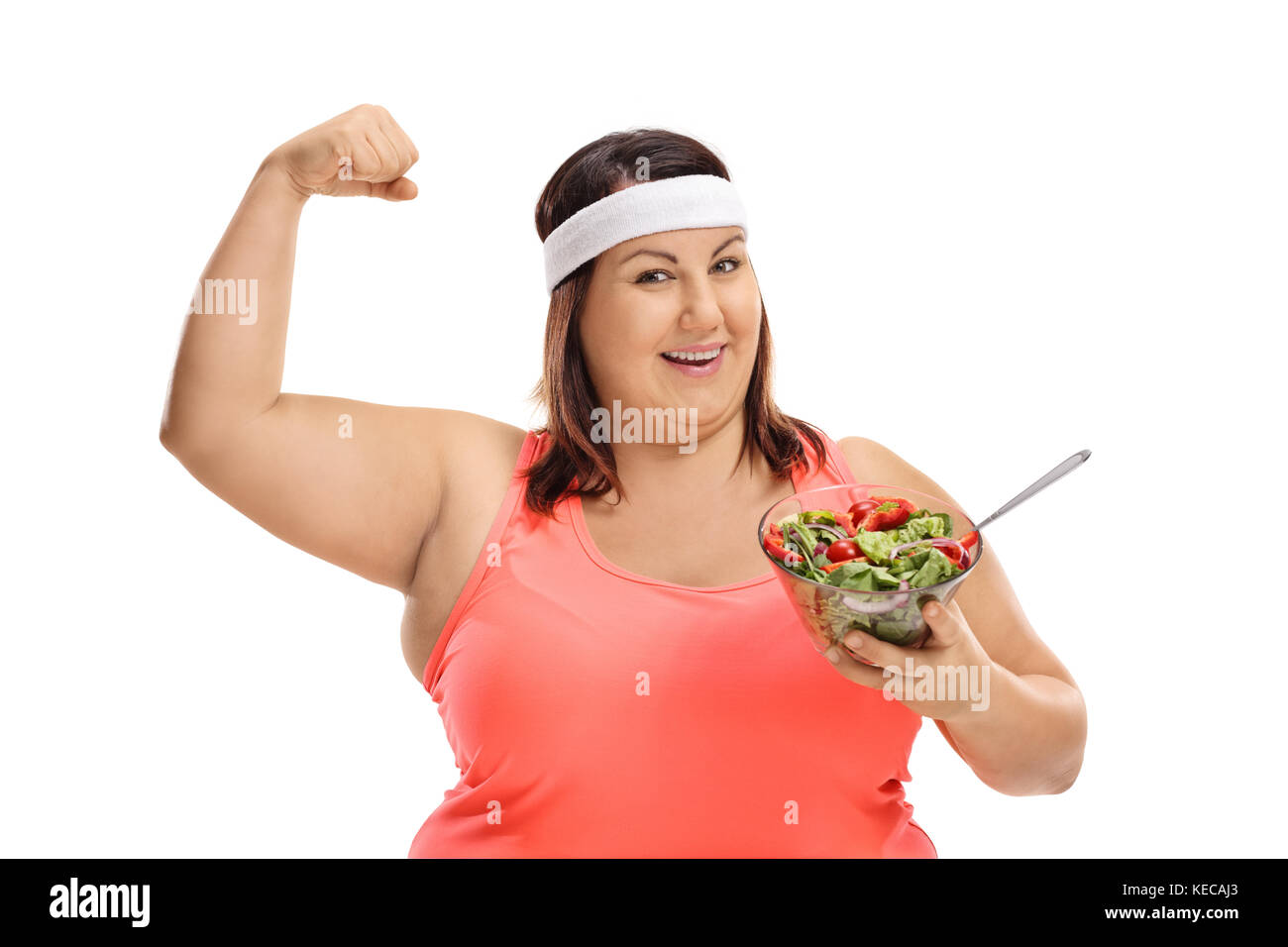 Donna sovrappeso tenendo un insalata e flettendo il suo bicipite isolato su sfondo bianco Foto Stock