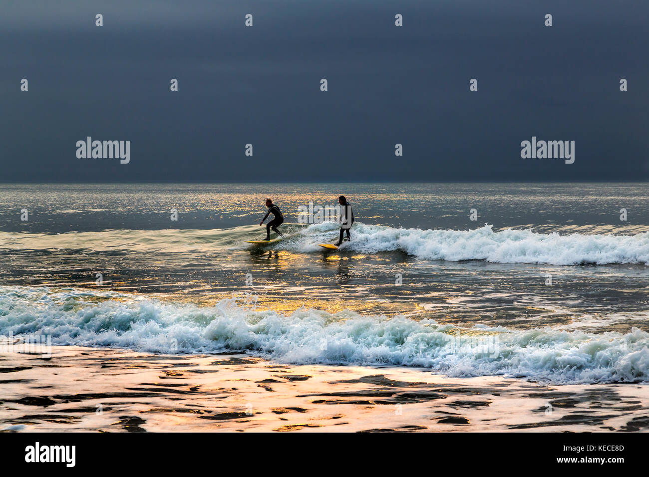 Surf vicino al molo di Bournemouth con il RISING SUN colata di un bagliore giallo sull'acqua Foto Stock