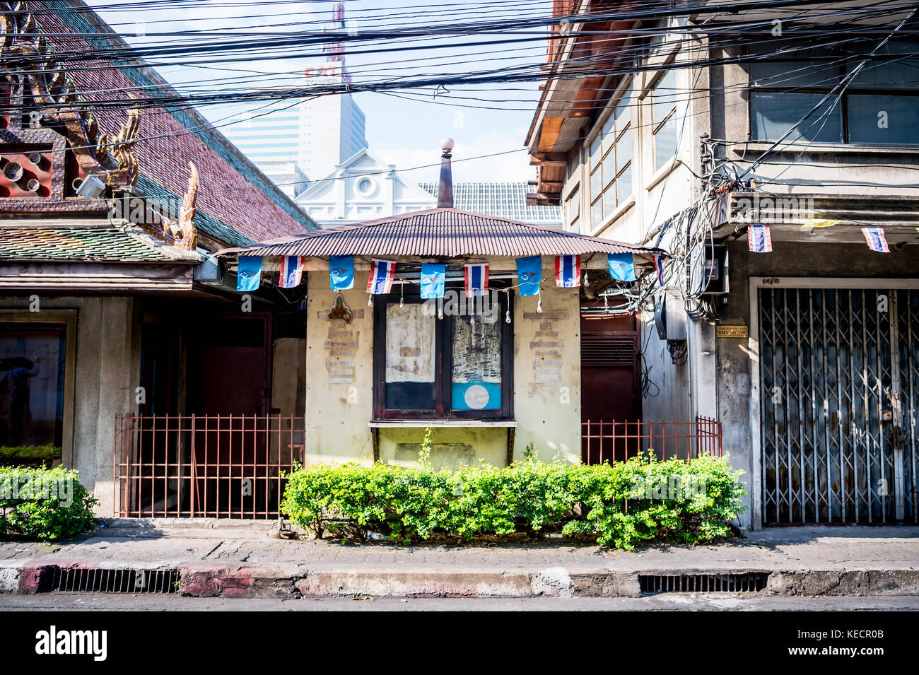 Un vecchio stile thai house si siede di fronte a un grattacielo moderno in una tranquilla strada a Bangkok in Tailandia del sud est asiatico. Foto Stock