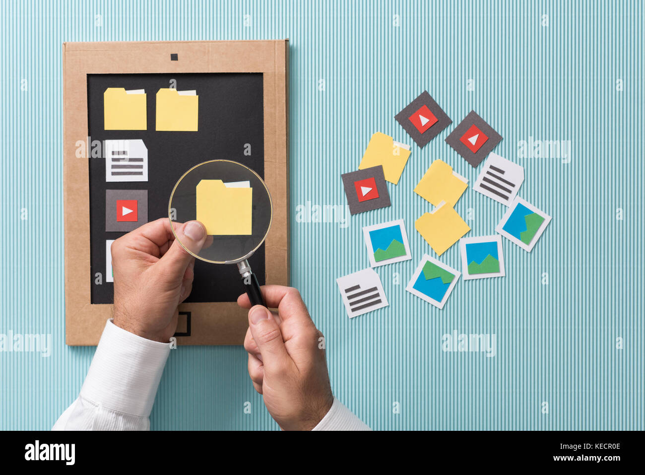 Per la selezione dei file, la gestione e l'organizzazione: utente analisi di carta tagliato le cartelle con una lente di ingrandimento e aggiungendo al suo cartone schermo tablet Foto Stock