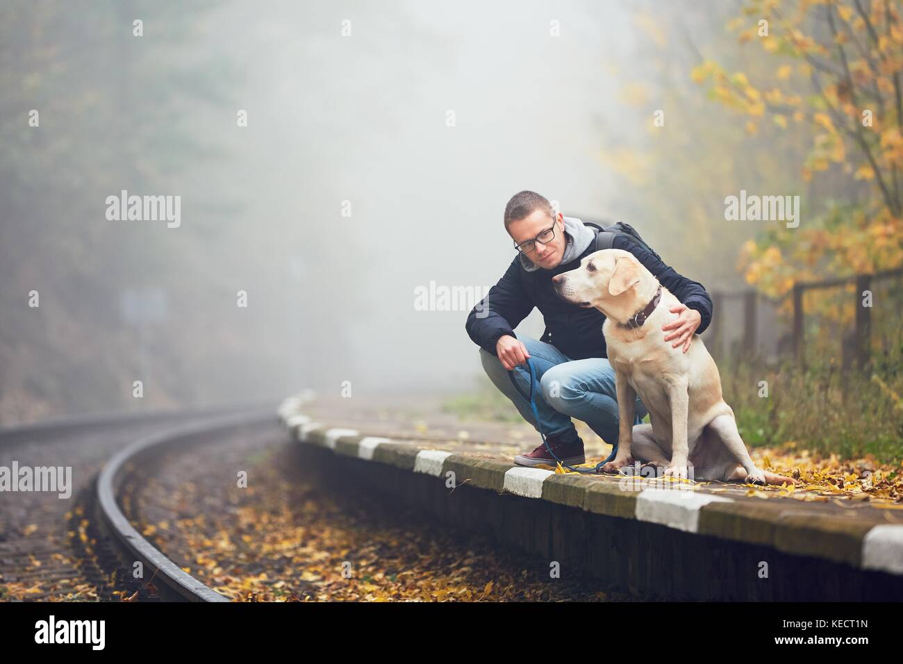 Vecchia Stazione ferroviaria nella nebbia. autunno umore sul viaggio. giovane uomo che viaggia con il suo cane in treno. Foto Stock
