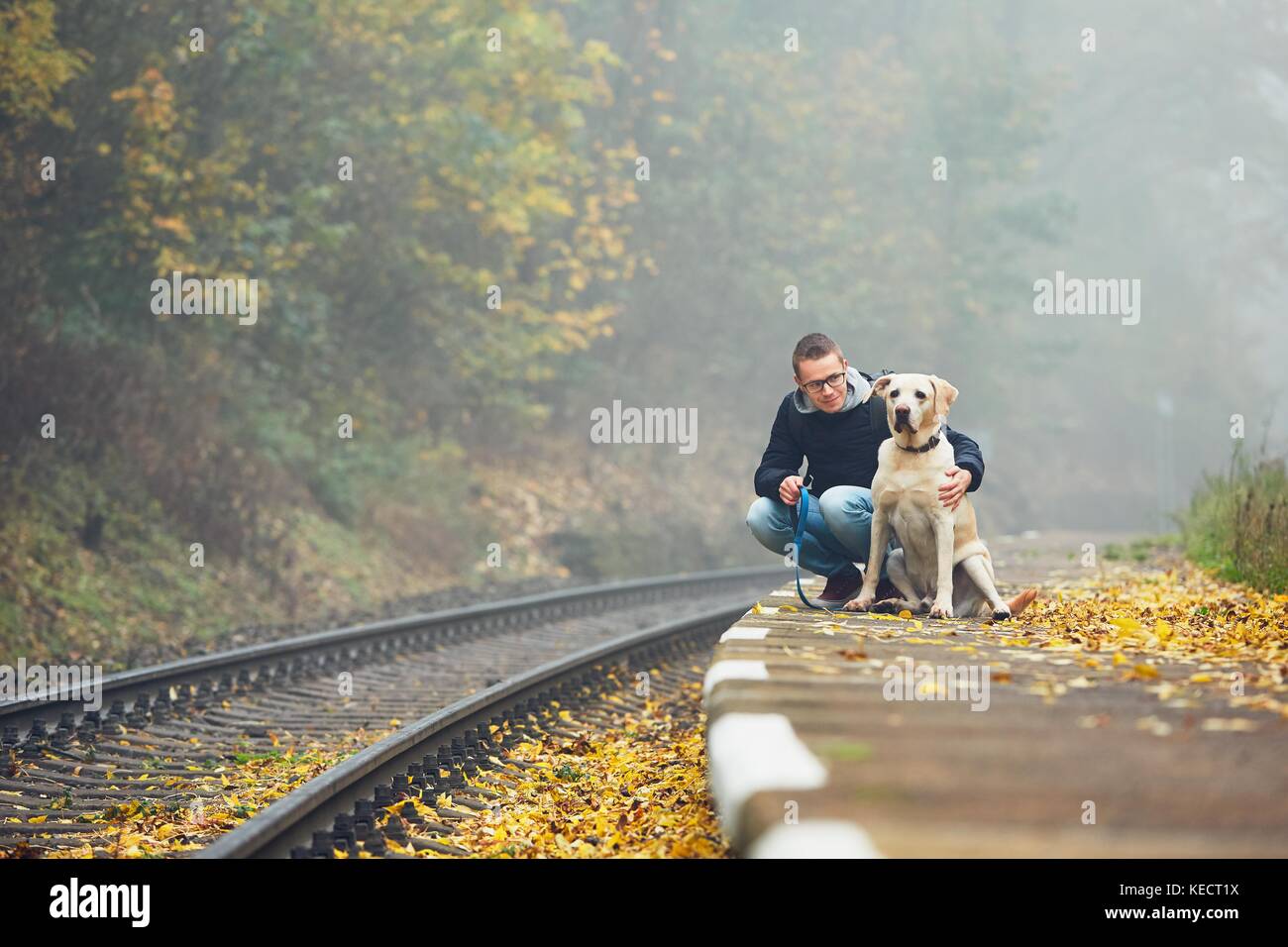 Vecchia Stazione ferroviaria nella nebbia. autunno umore sul viaggio. giovane uomo che viaggia con il suo cane in treno. Foto Stock