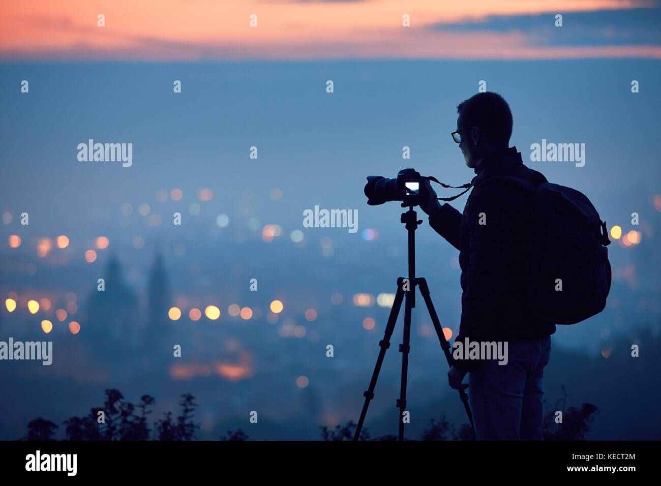 Silhouette del fotografo con treppiede. giovane uomo prendendo foto con la sua macchina fotografica nella città di notte. Praga, Repubblica ceca. Foto Stock