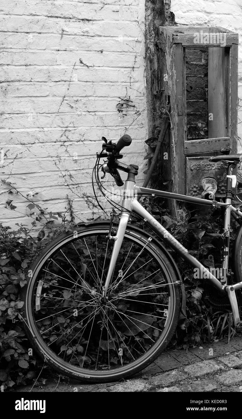 Giugno 2017 - moderna bicicletta bici sinistra appoggiata contro un vecchio muro a Thame, Oxfordshire, Inghilterra. Foto Stock
