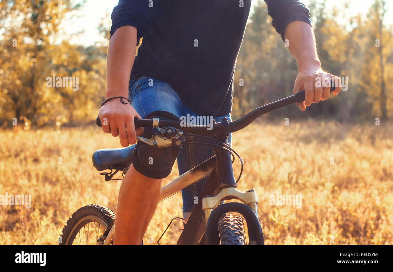 Close-up della mano di un giovane atleta sulla ruota di una bicicletta in tempo soleggiato all'esterno. Foto Stock