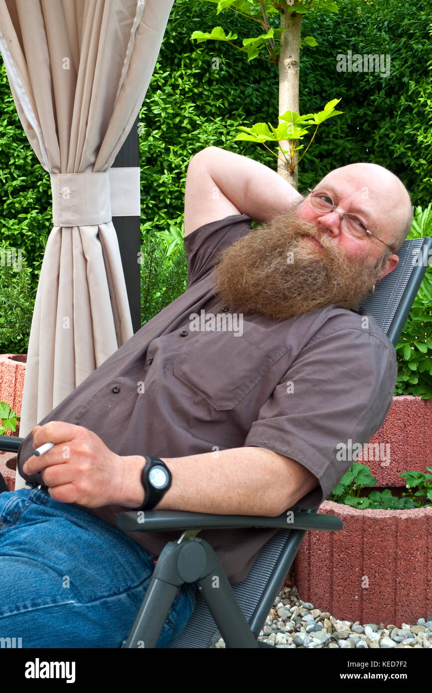 Mann mit langem Bart erholt sich im Liegestuhl Foto Stock