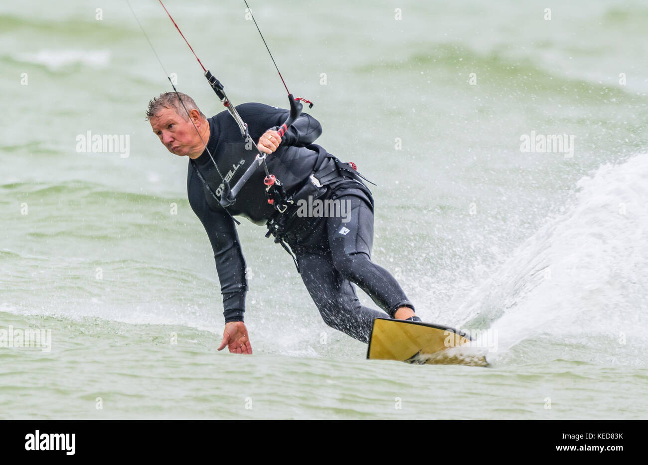 Uomo di eseguire un giro mentre il kitesurfing in mare in una giornata di vento. Kitesurfer maschio sull'oceano. Foto Stock