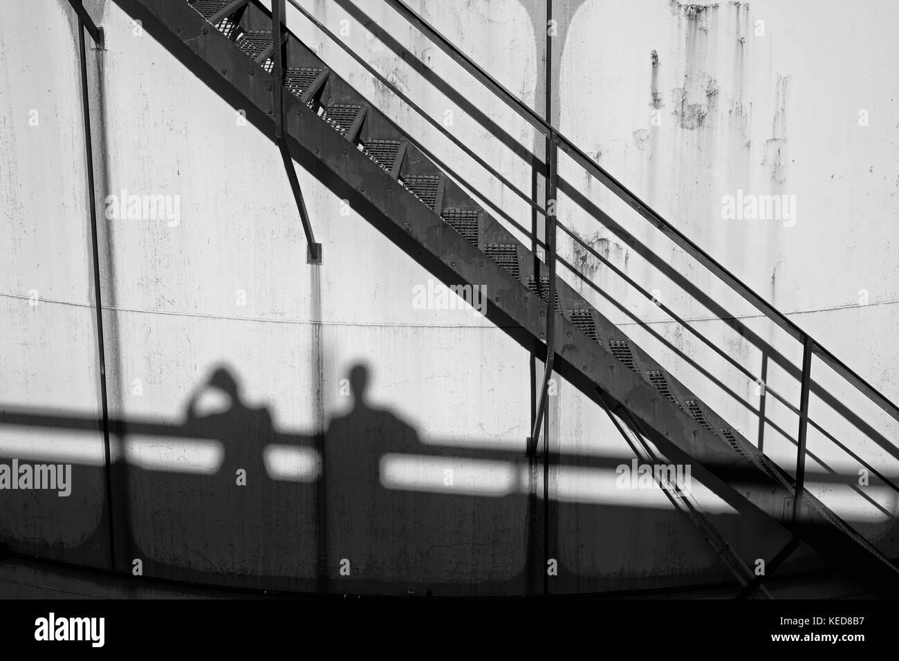 Persone ombre sui vecchi serbatoi in metallo in Power Plant, il vecchio tipo di impianto di fabbrica. struttura in metallo con la vecchia vernice gialla e rusty luoghi. cerchio di ferro la Foto Stock